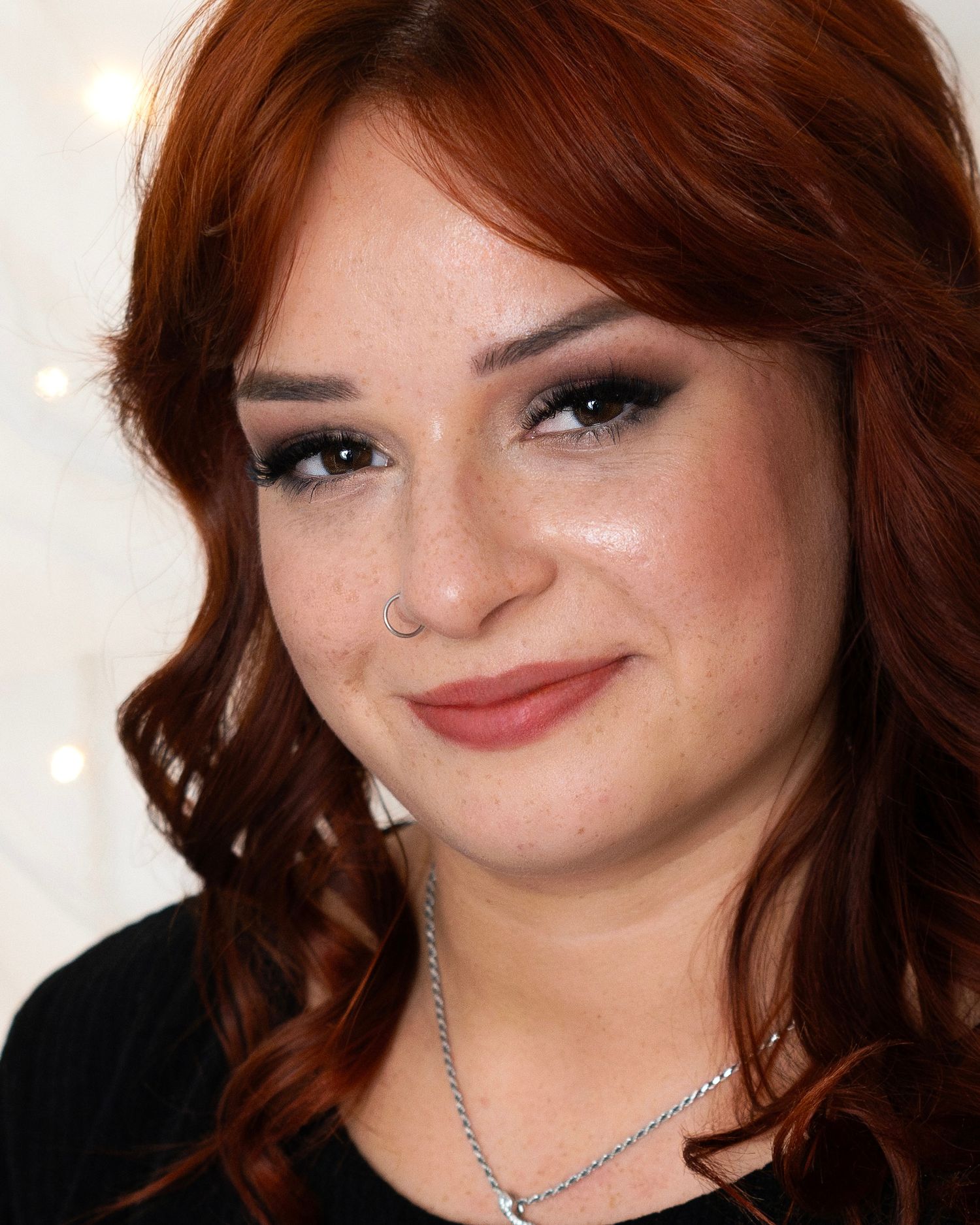 Close-up portrait with winged eyeliner, soft makeup and auburn waves.