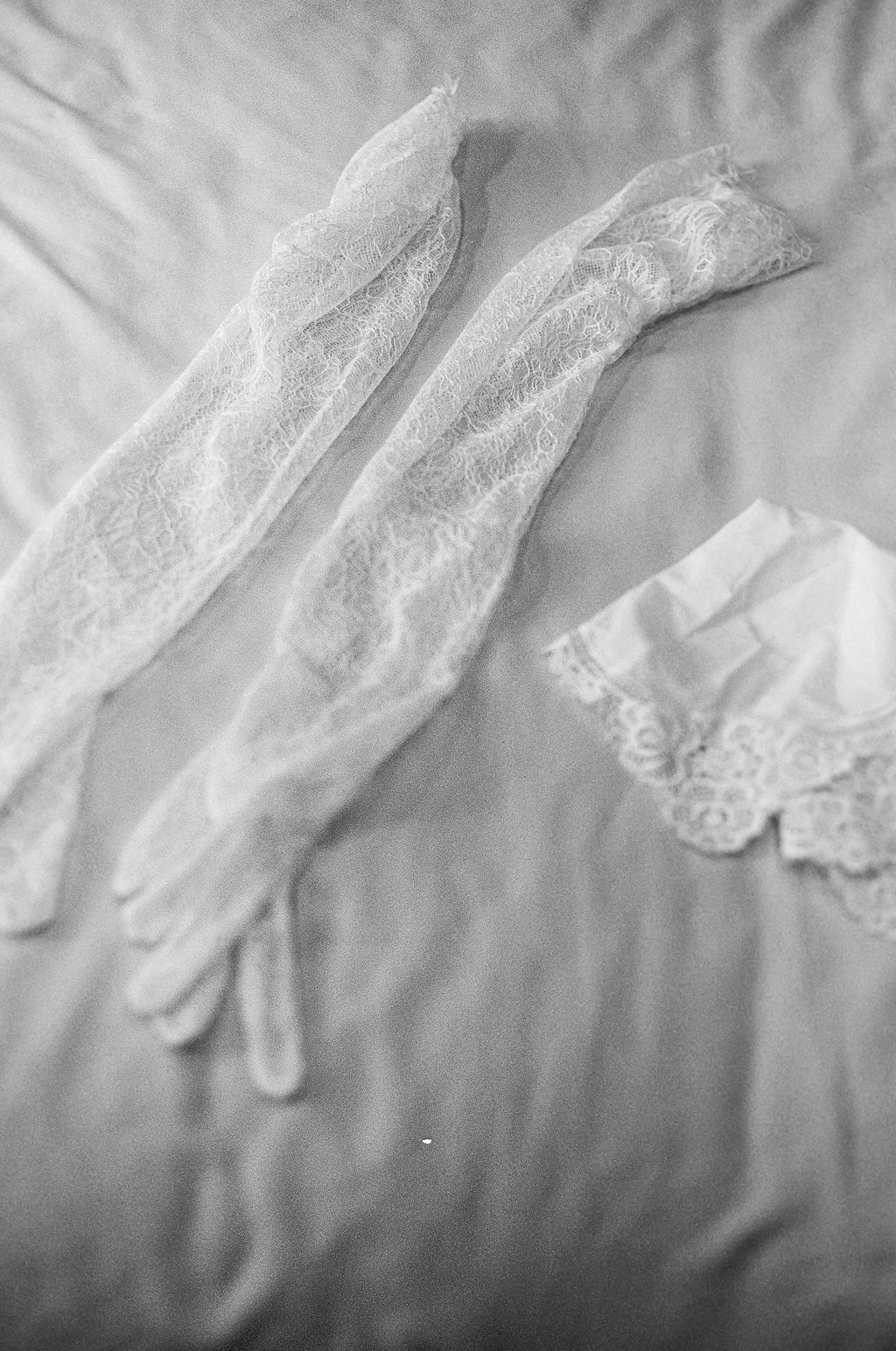 A series of vintage white lace gloves arranged in a delicate horizontal display against a soft gray background.