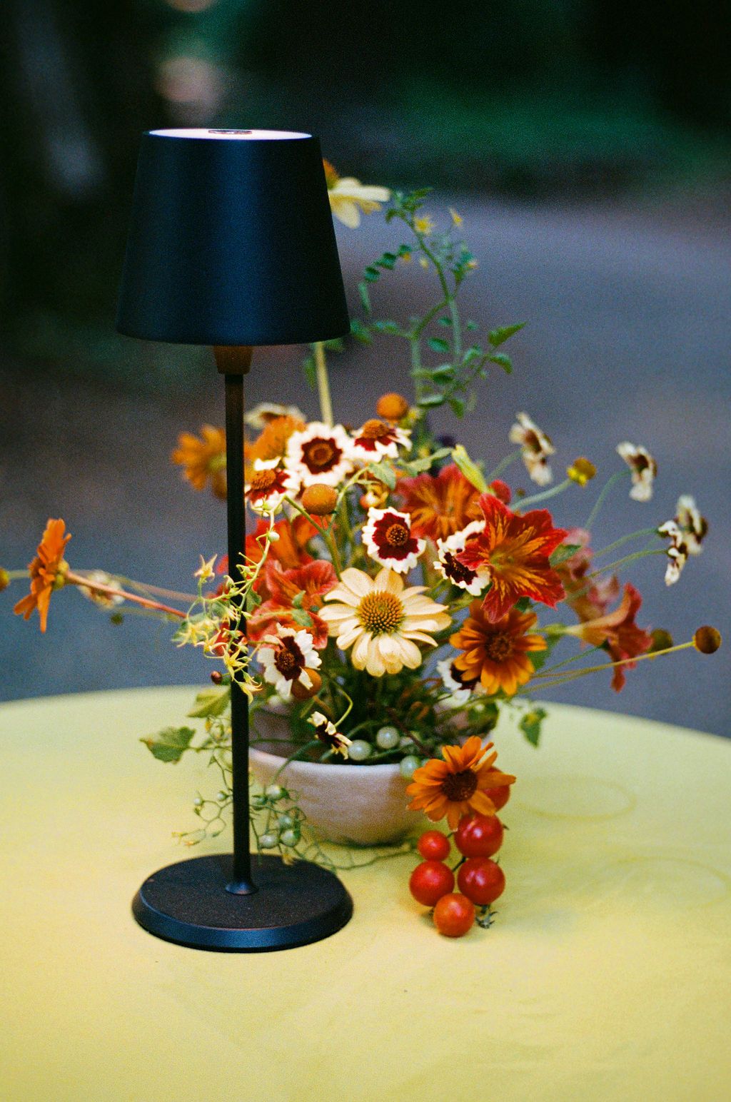 Decorative floral arrangement with orange and white flowers next to a table lamp.