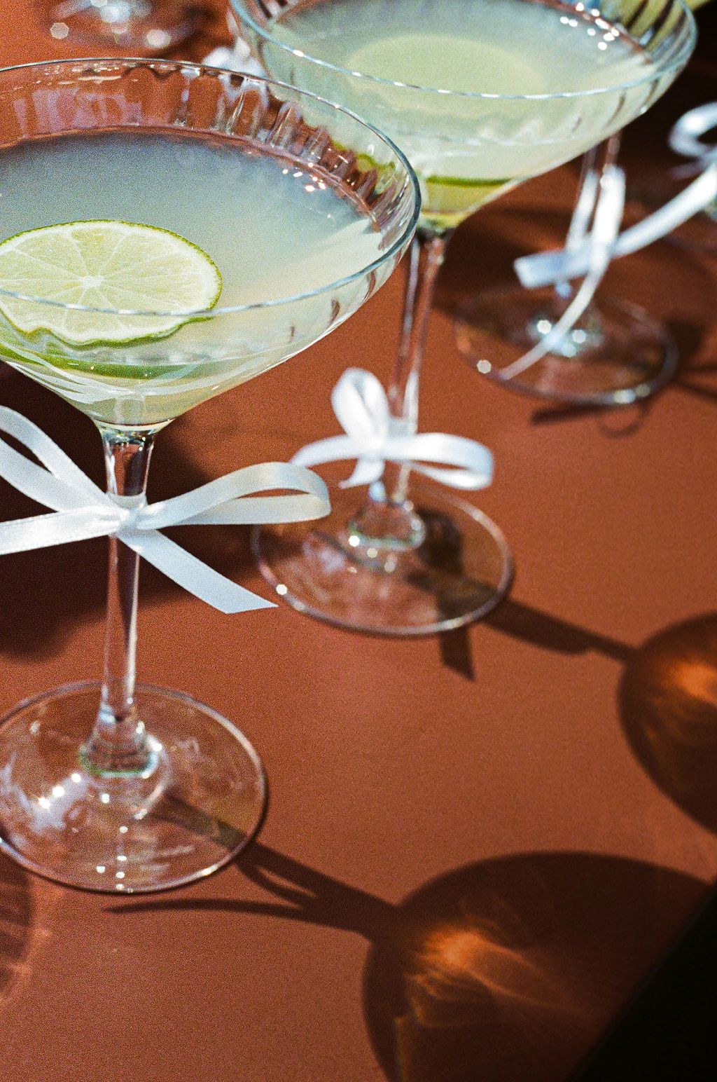 Elegant martini glasses garnished with lime slices are arranged on a wooden surface.