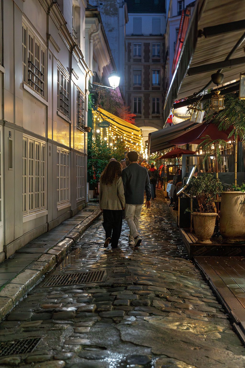 Cobblestone street at night with illuminated storefronts and historic buildings in a European city in Paris.