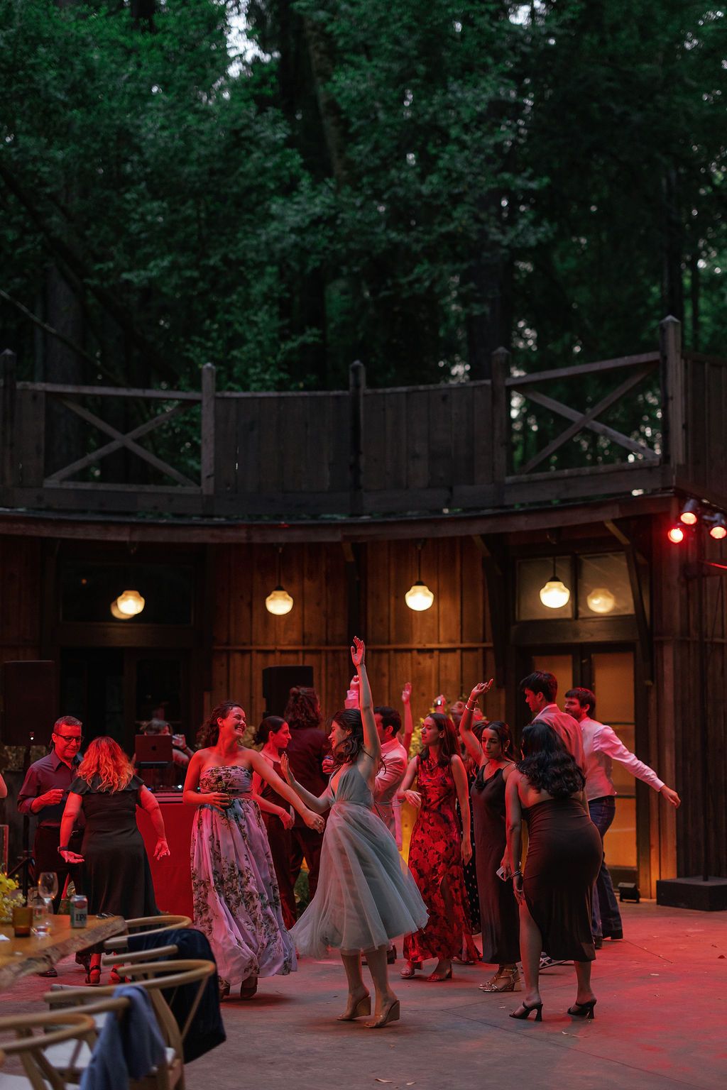 Outdoor wedding reception venue with string lights and wooden walls at dusk.