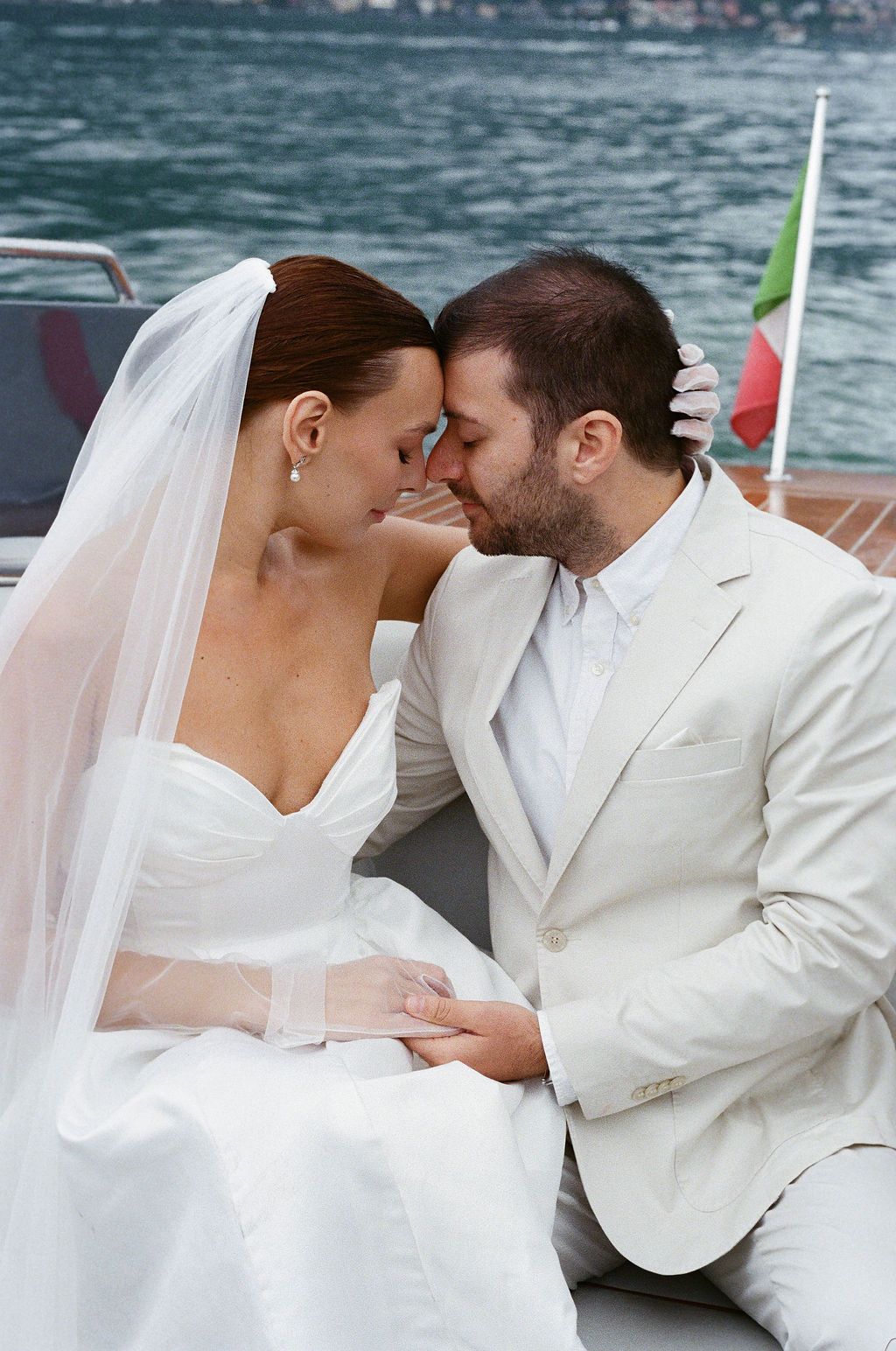 Romantic wedding couple shares intimate moments on a boat with a scenic lake backdrop in Lake Como.