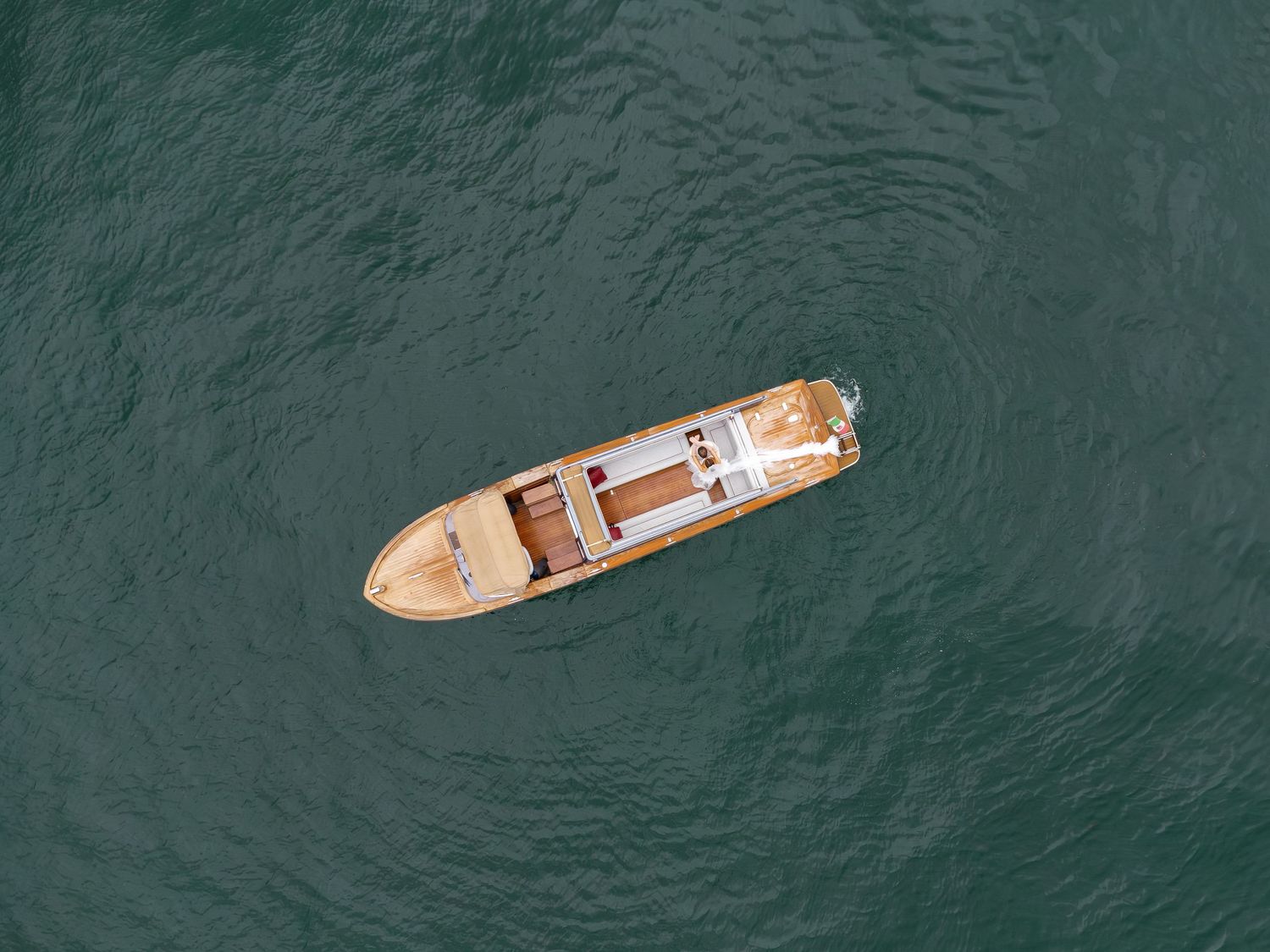Aerial top-down view of a wooden boat floating on calm turquoise ocean water.