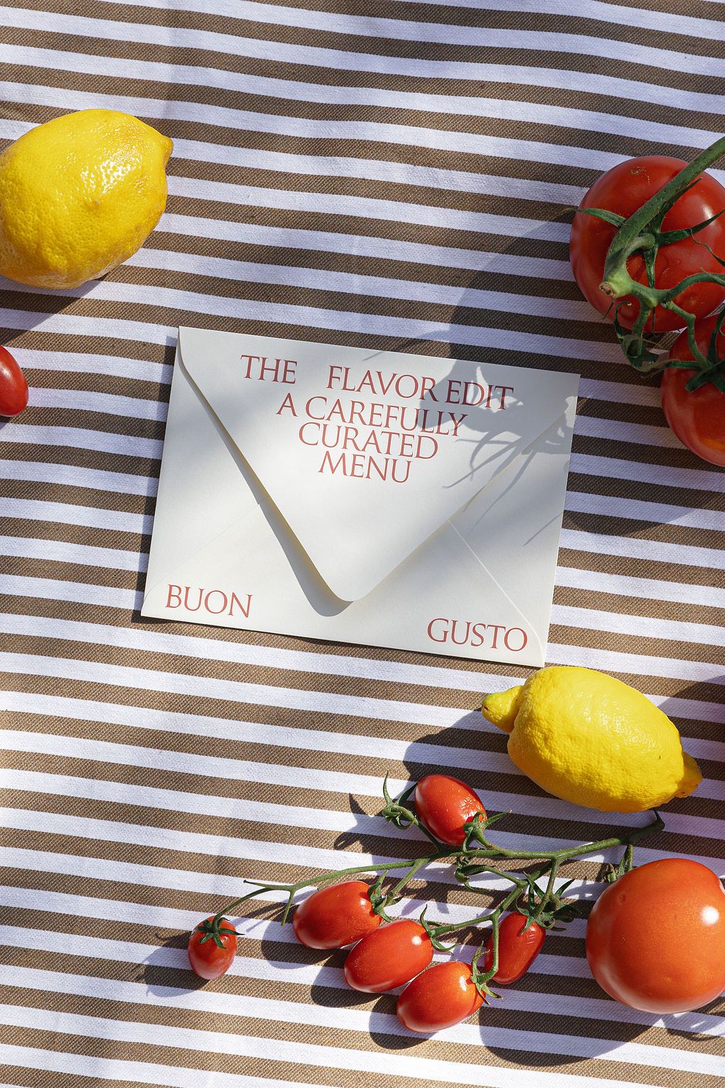 Fresh yellow lemons and vine-ripened tomatoes arranged on a brown and white striped background with text cards in Tuscany, Italy.