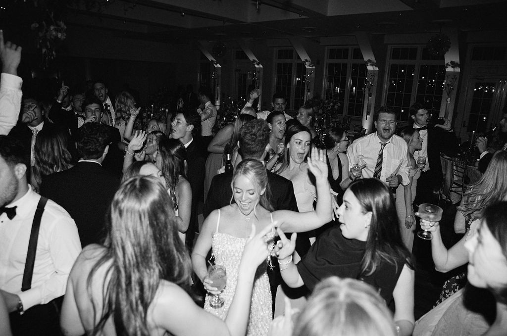 Lively crowd dancing and celebrating at a dimly lit wedding reception on Long Island.