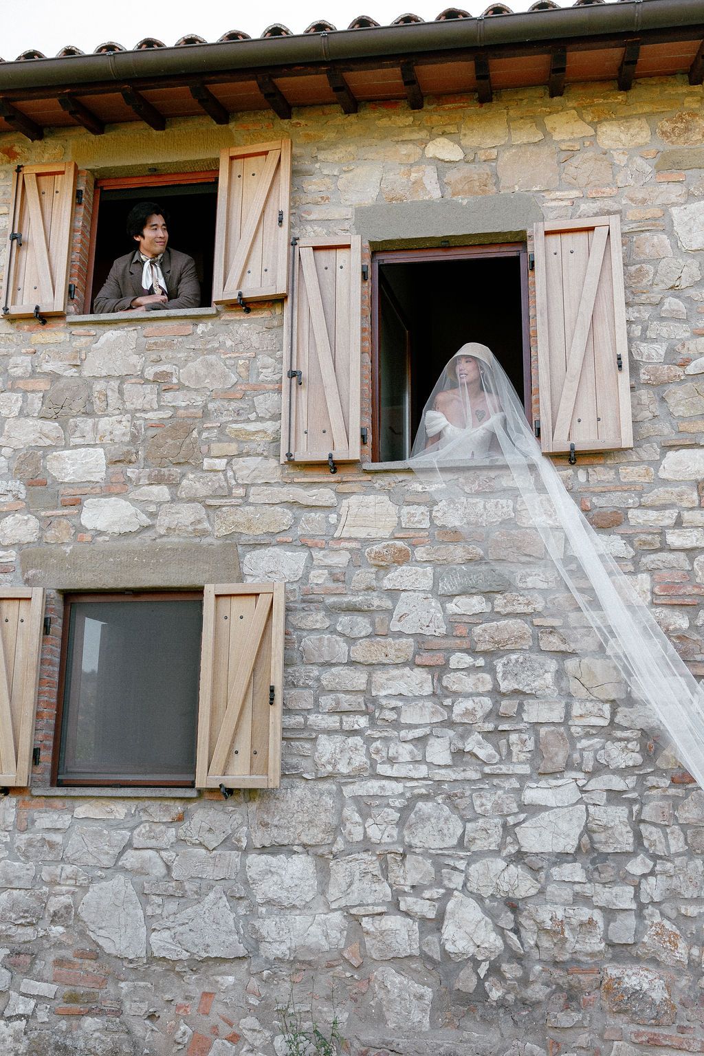 Stone farmhouse exterior with wooden shuttered windows and architectural details in Tuscany, Italy.