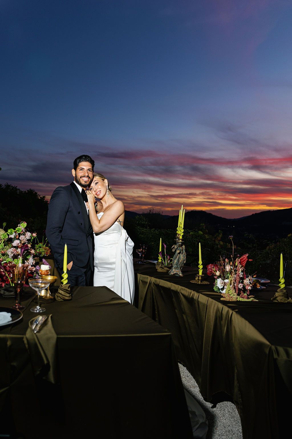 Silhouetted couple embracing against dramatic sunset sky at outdoor venue in Portugal.