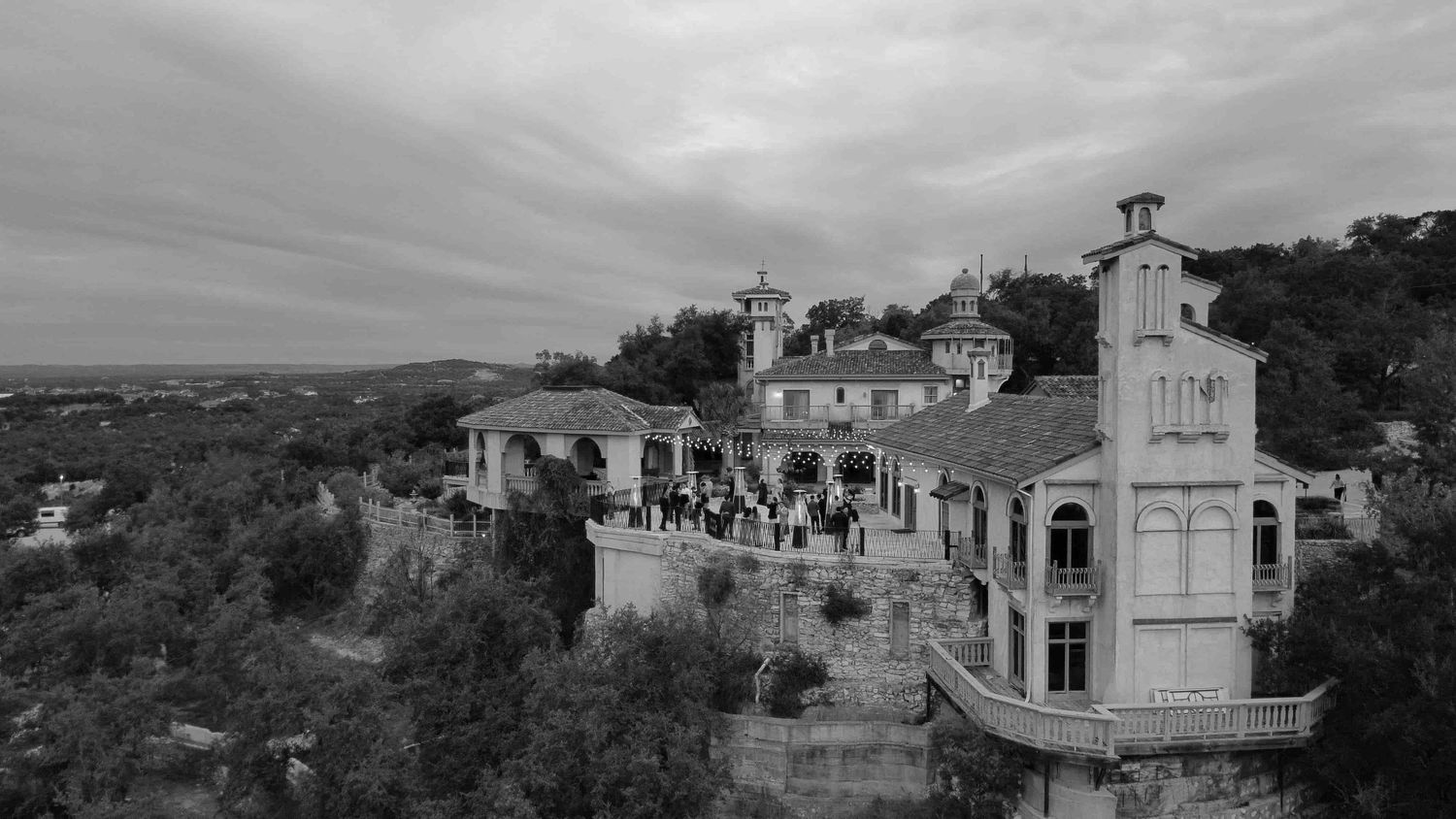 A panoramic black and white photograph showing a mountainside village with traditional stone buildings and winding paths.