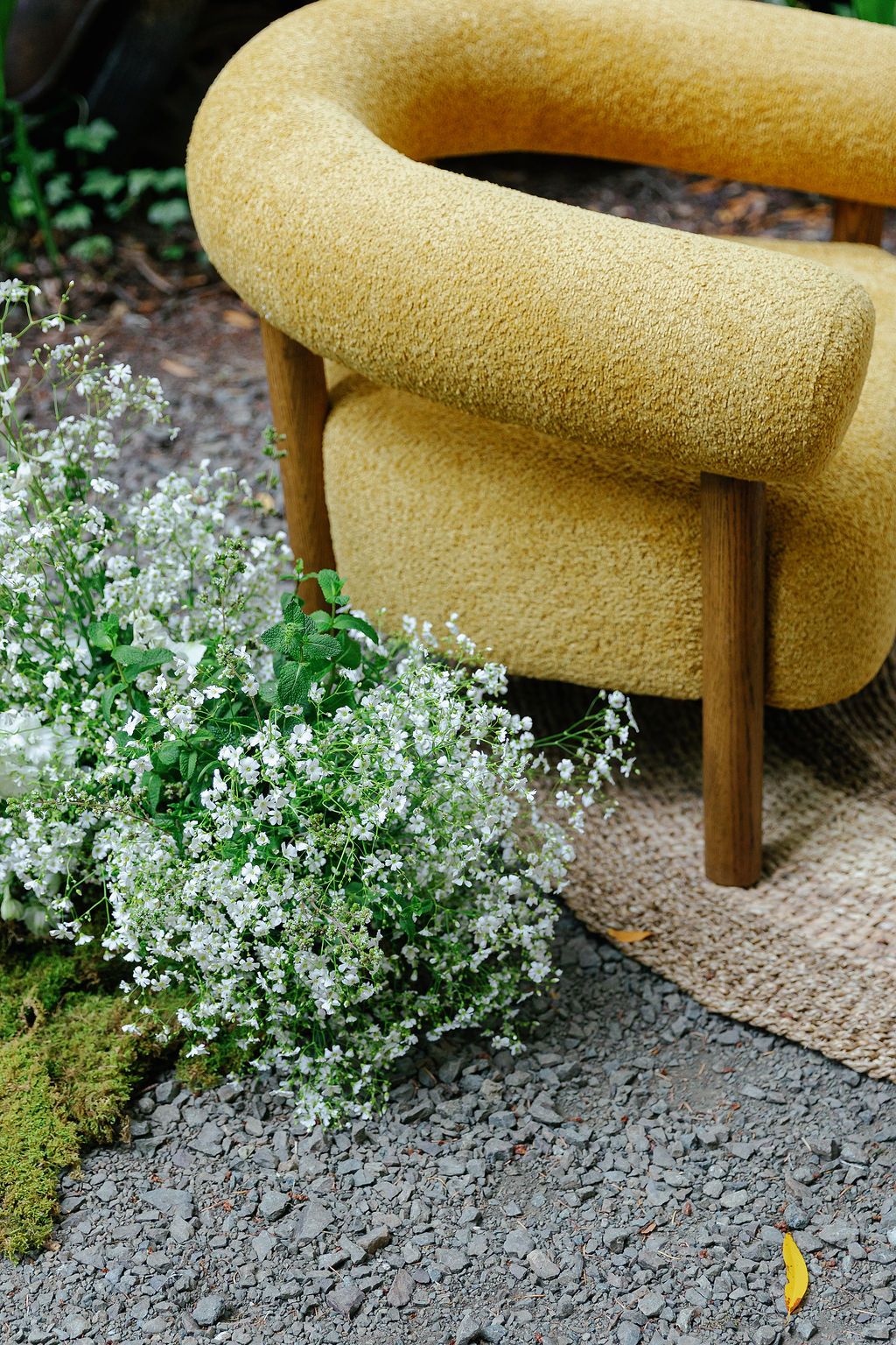 Yellow upholstered bench or settee with delicate white flowers blooming at its base.