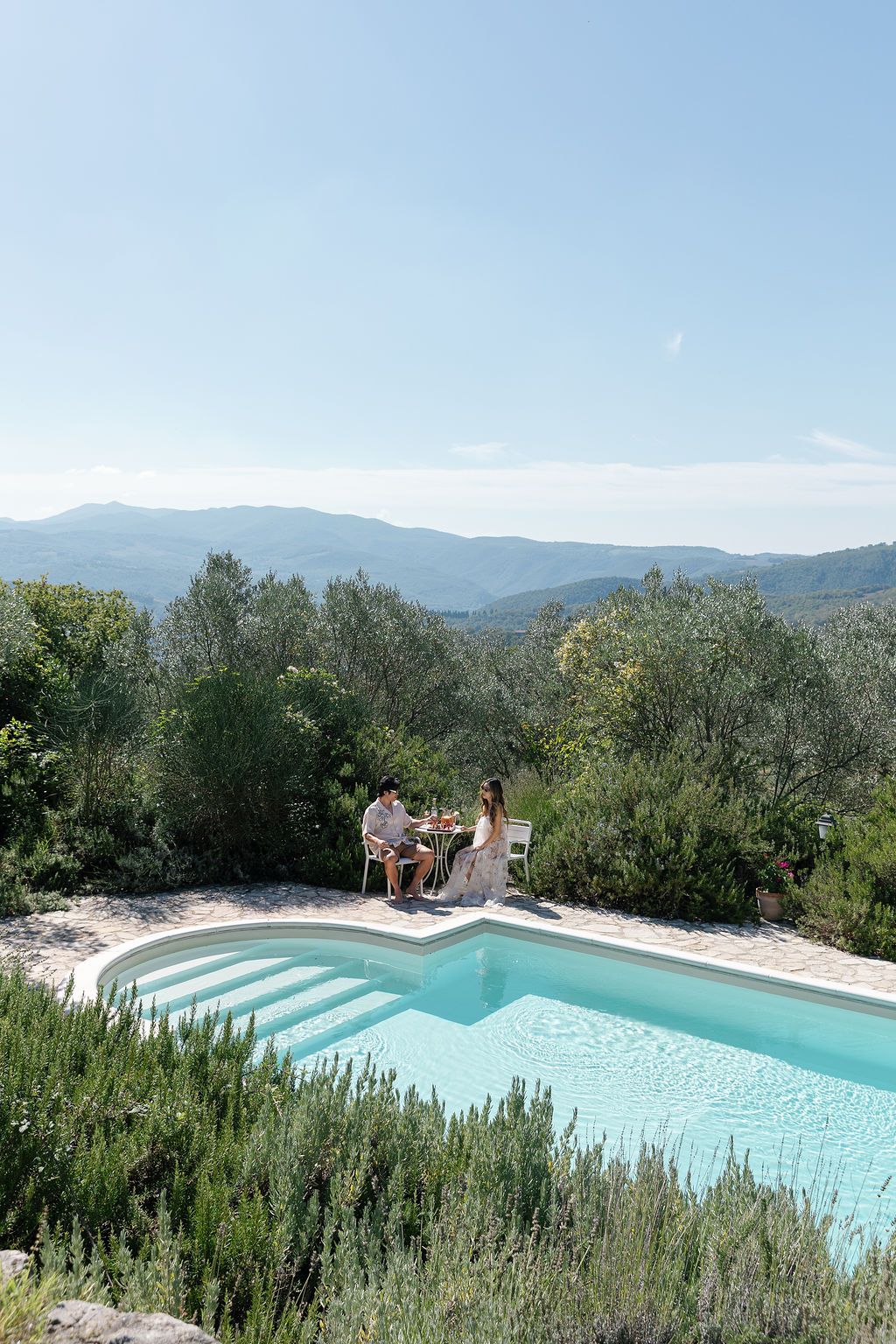 A stunning infinity pool overlooking rolling hills and mountains with olive groves in the background in Tuscany, Italy.