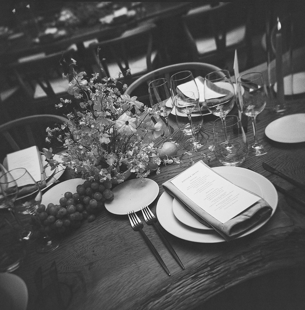 Black and white photo of an elegant wedding table setting with floral centerpieces and place settings.