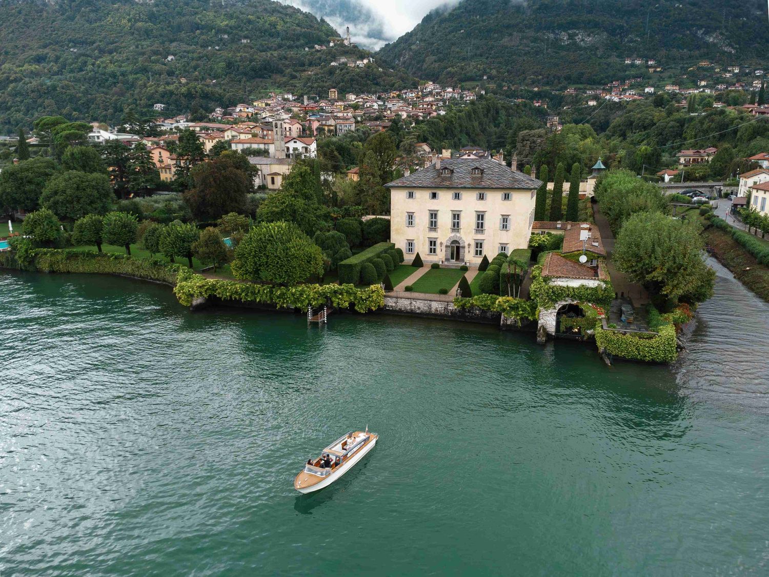Scenic aerial view of Lake Como shoreline with luxury Villa Balbiano and boats nestled among lush greenery in Italy.