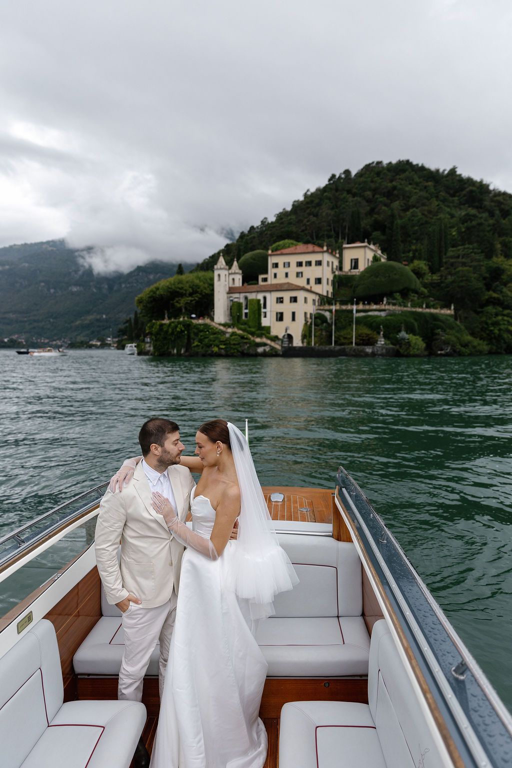 Wedding couple on luxury boat with Italian villa and Lake Como in the background.