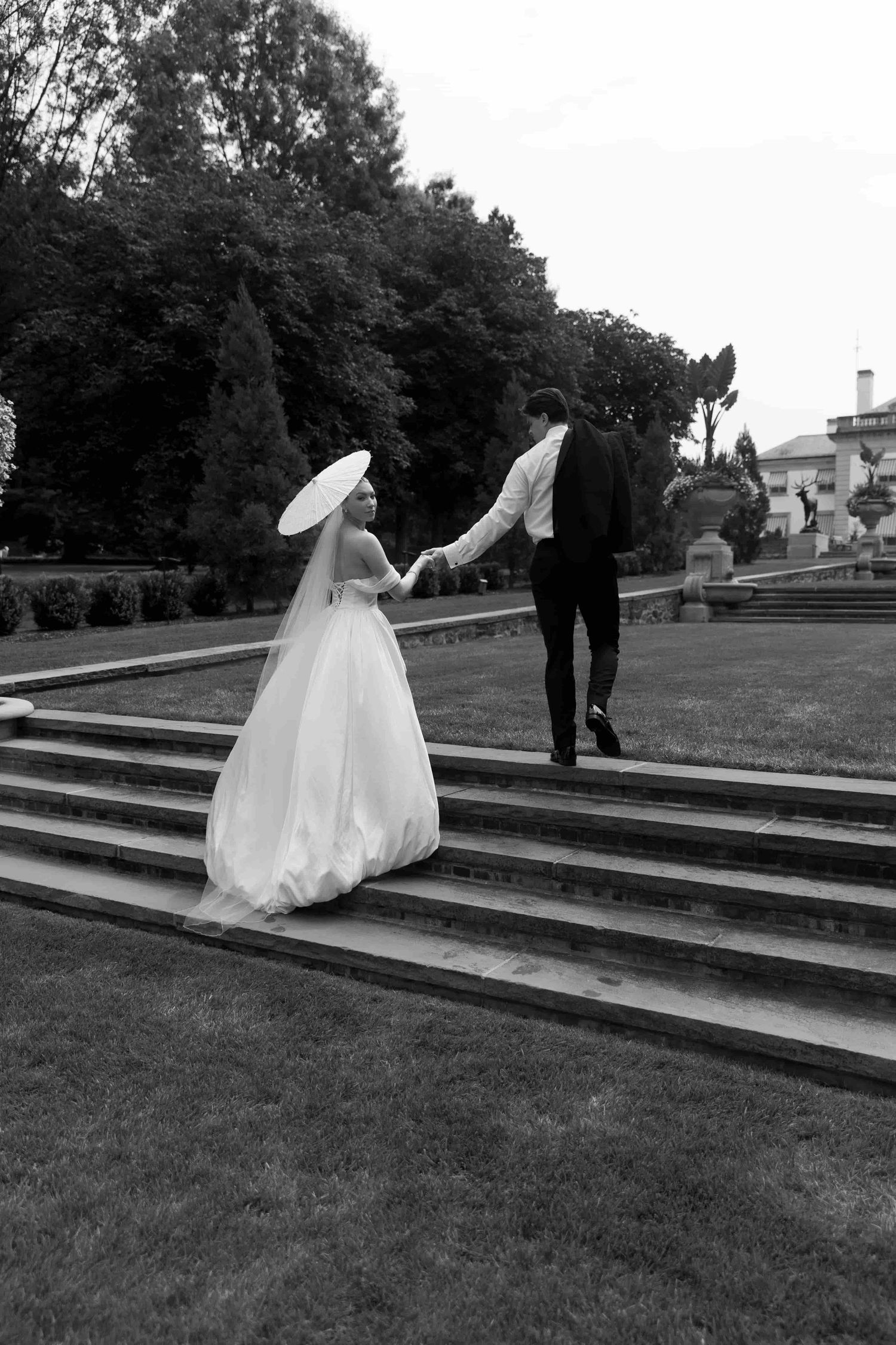 A sequence showing a figure in a flowing white wedding dress playfully rolling down grassy stone steps in black and white.