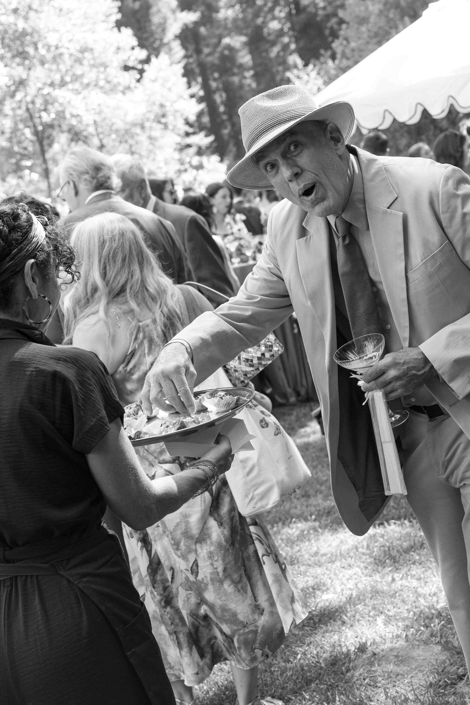 Black and white photo of elegantly dressed guests socializing outdoors at a garden party event.