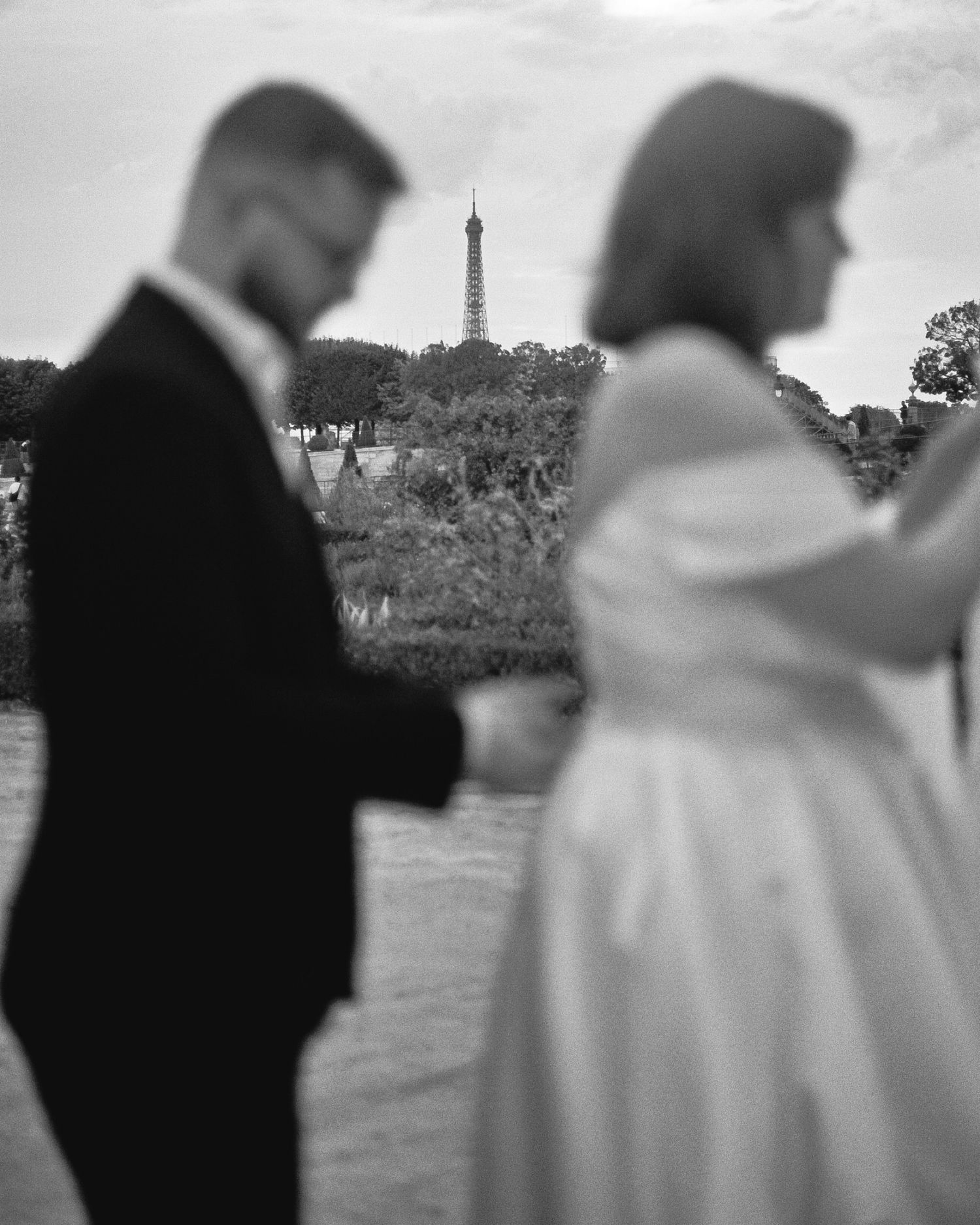 A romantic black and white silhouette of a couple standing apart with the Eiffel Tower visible in the background.