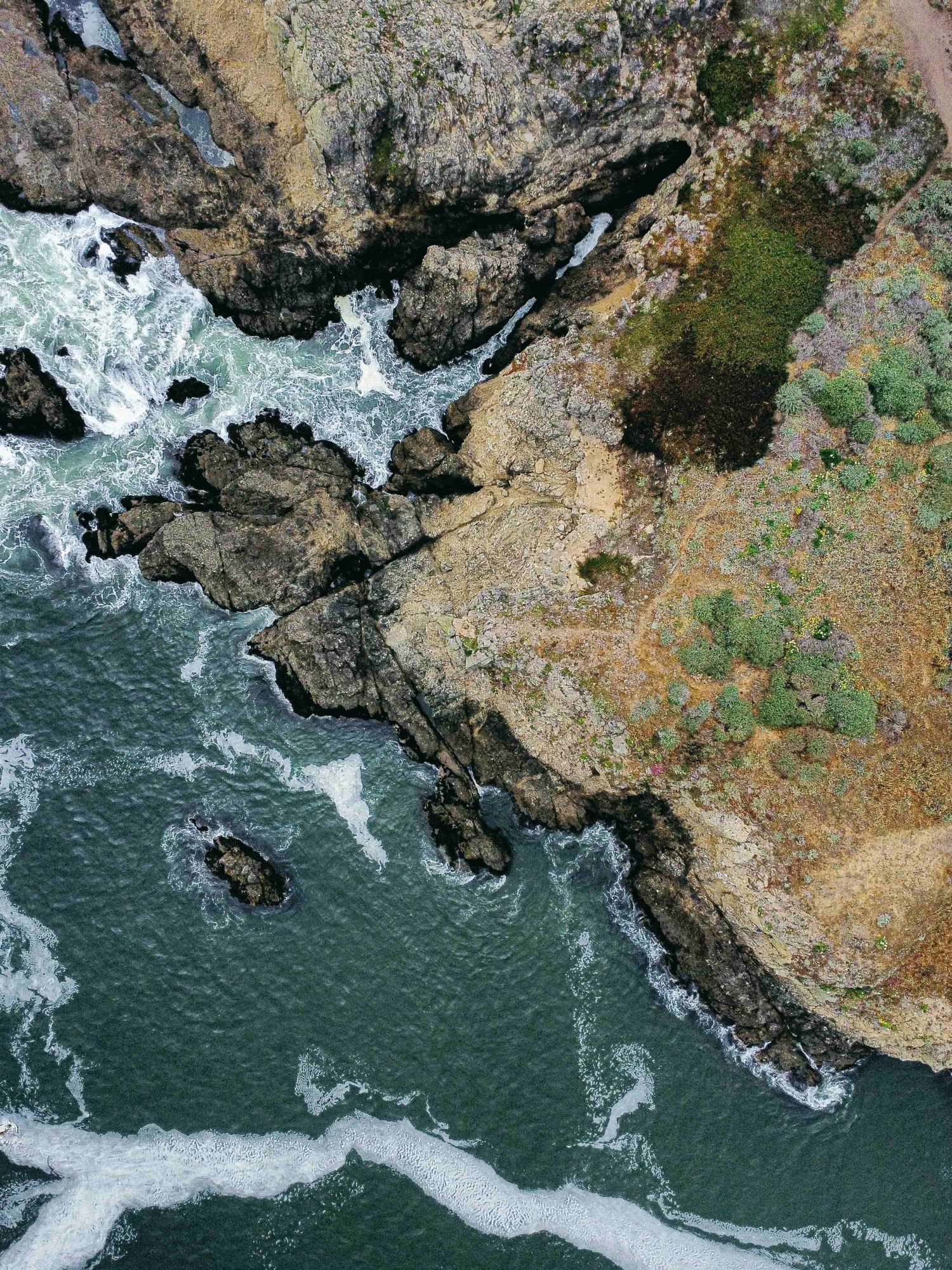 Aerial view of a turbulent river with white rapids flowing through rugged rocky cliffs and green vegetation along the banks.