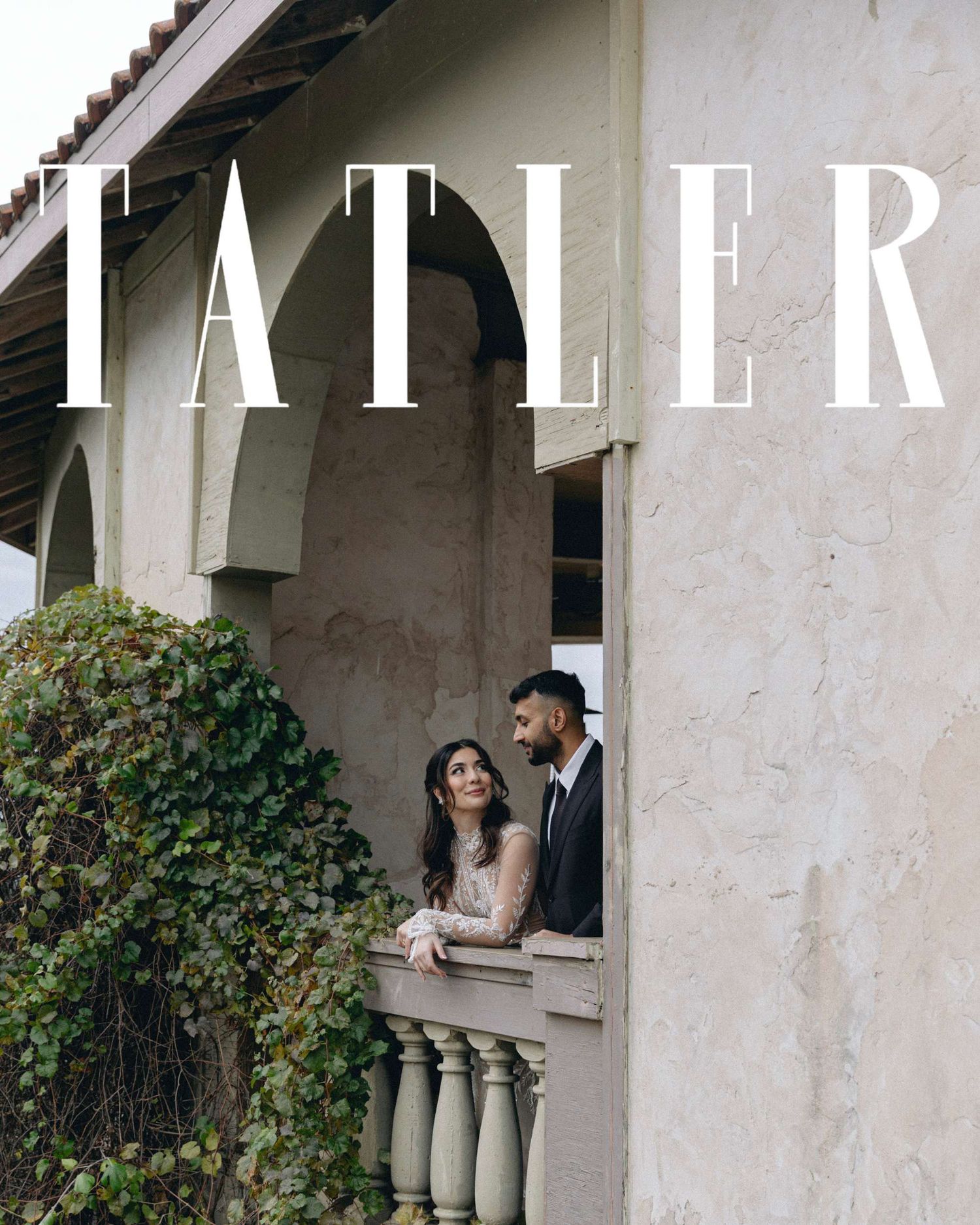 A couple shares a romantic moment in an elegant white stone archway with climbing vines and greenery in Texas.