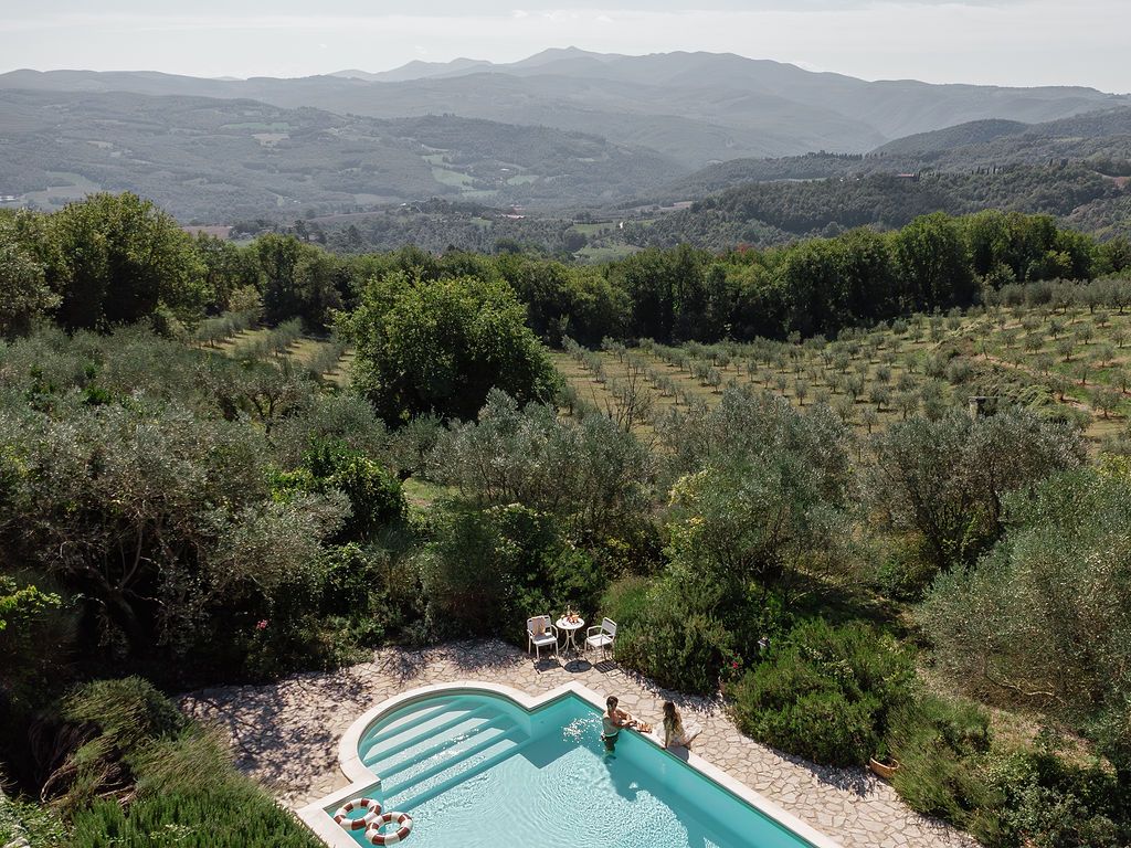 Scenic swimming pool overlooking rolling hills and olive groves in the Tuscan countryside.