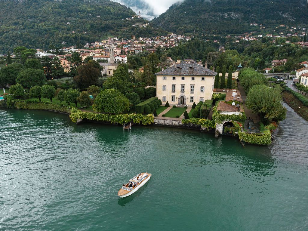 Aerial view of Lake Como with luxury villas and mountains in the background on a cloudy day.