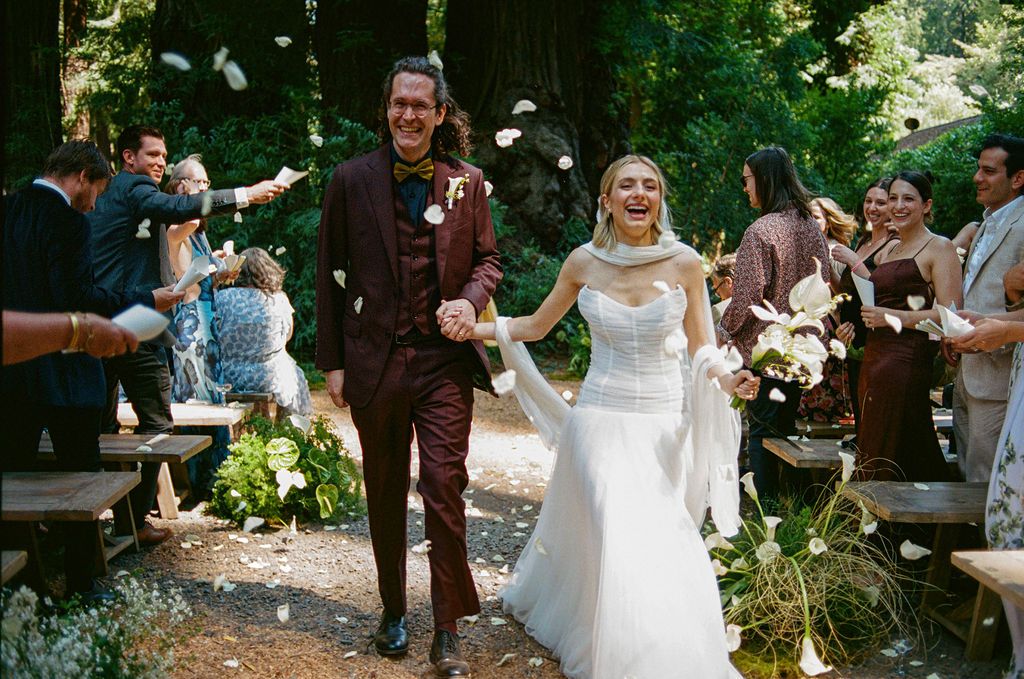 A joyful outdoor wedding ceremony in a lush forest setting with the couple celebrating among guests in California.