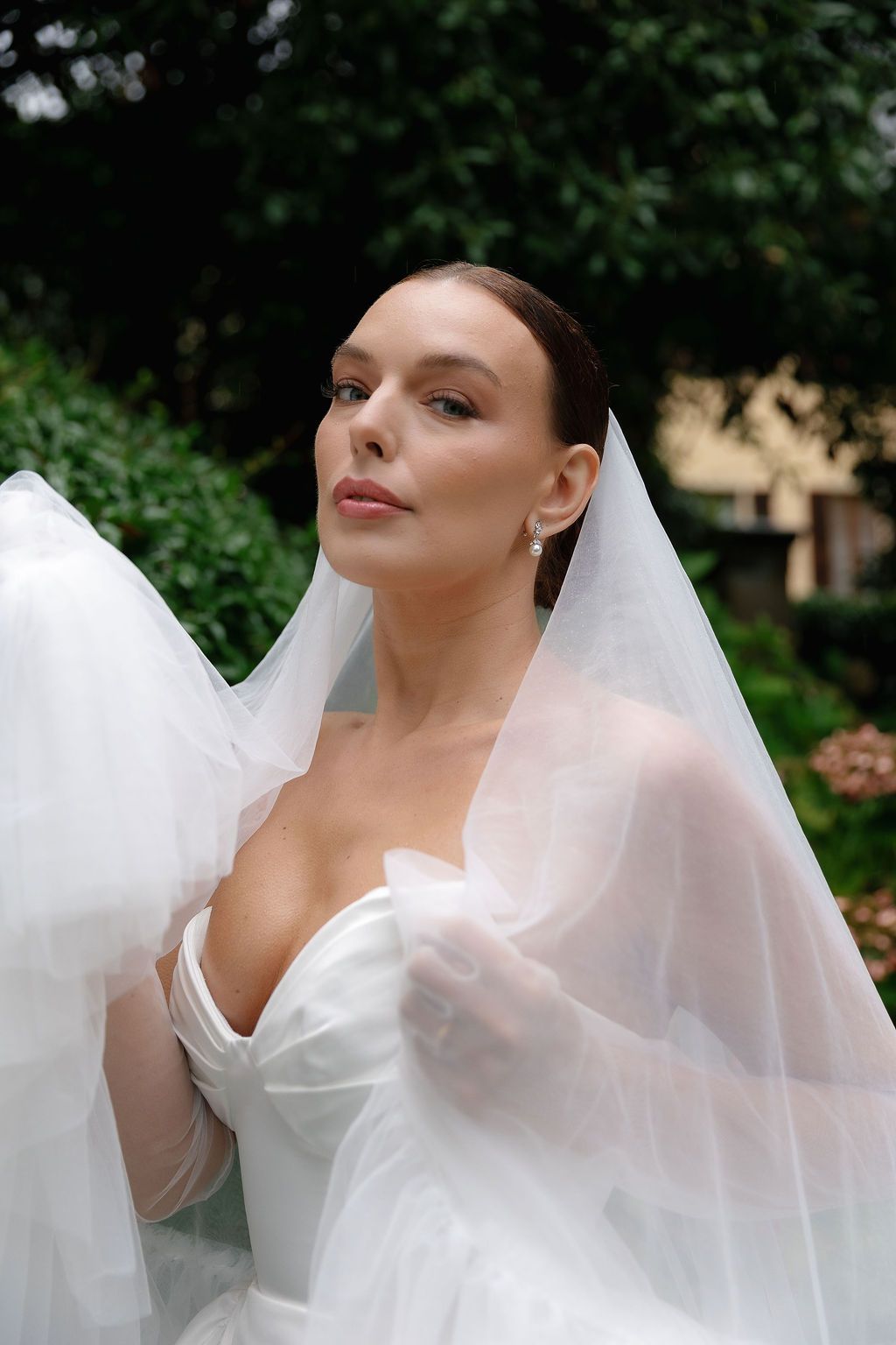 Elegant bridal portrait featuring a strapless white gown and flowing veil in a garden setting in Lake Como.