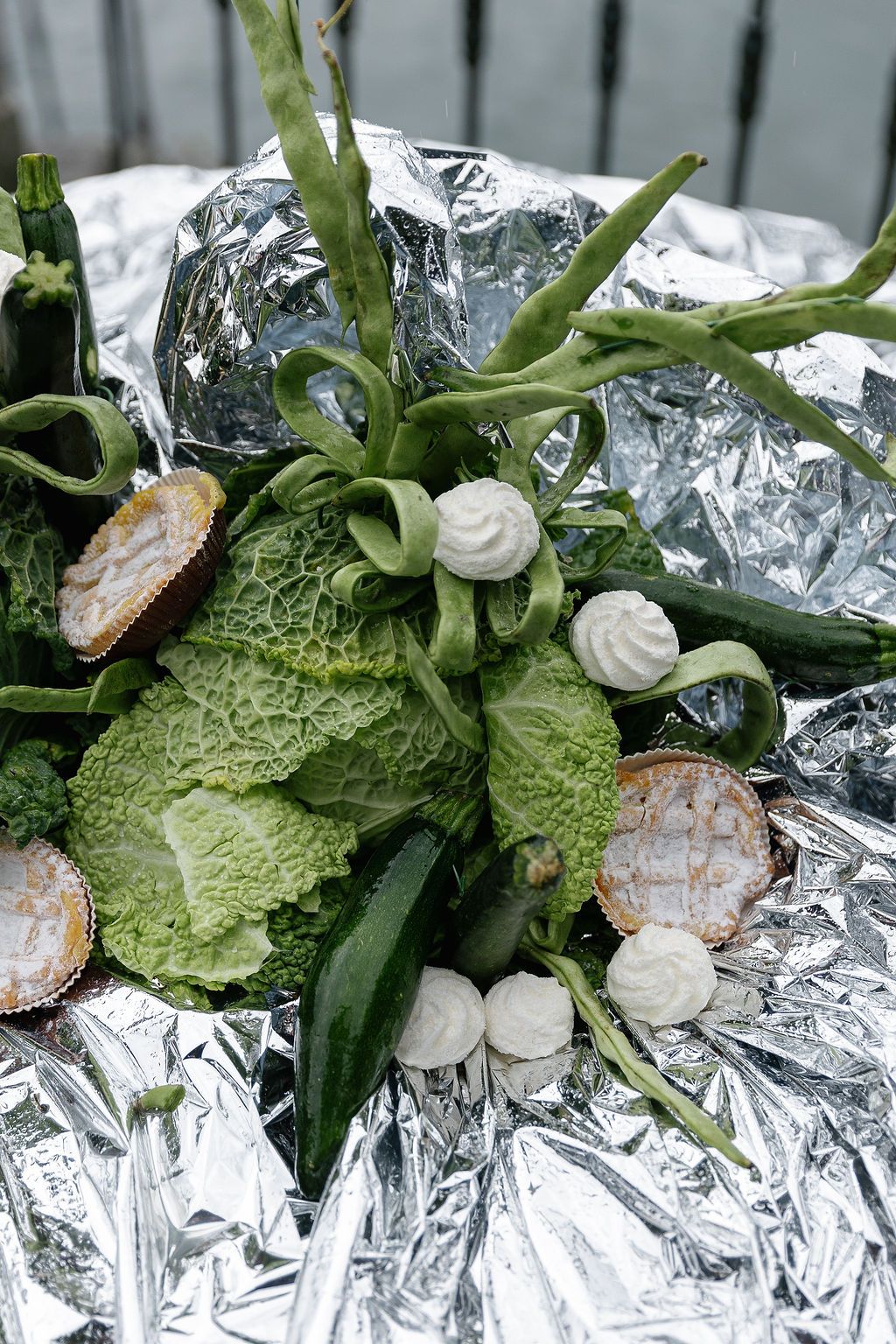 Fresh savoy cabbage leaves garnished with white cream dollops and citrus slices on reflective silver foil surface in Lake Como.