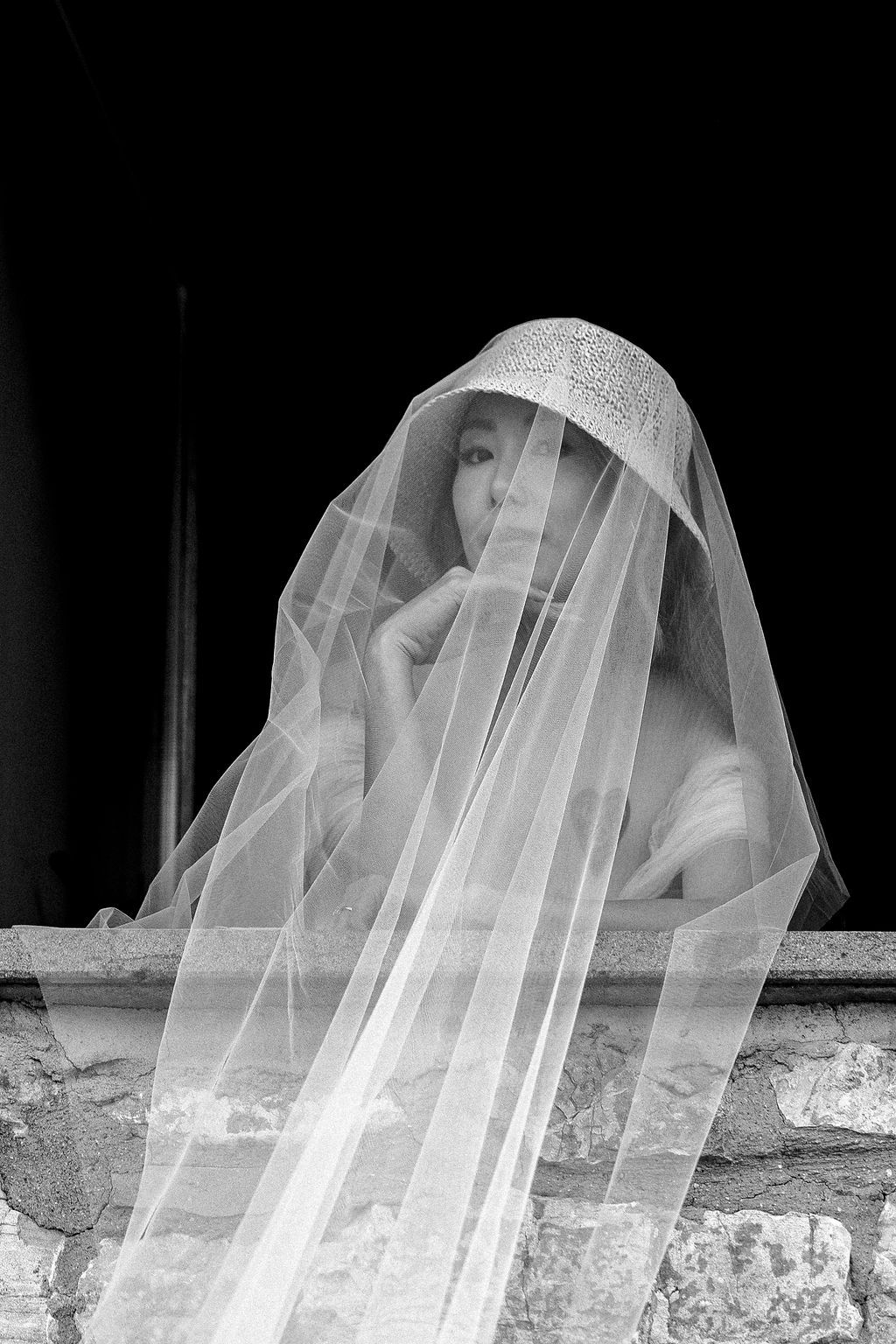 Artistic black and white photograph of flowing wedding veil against textured stone wall in Tuscany, Italy.
