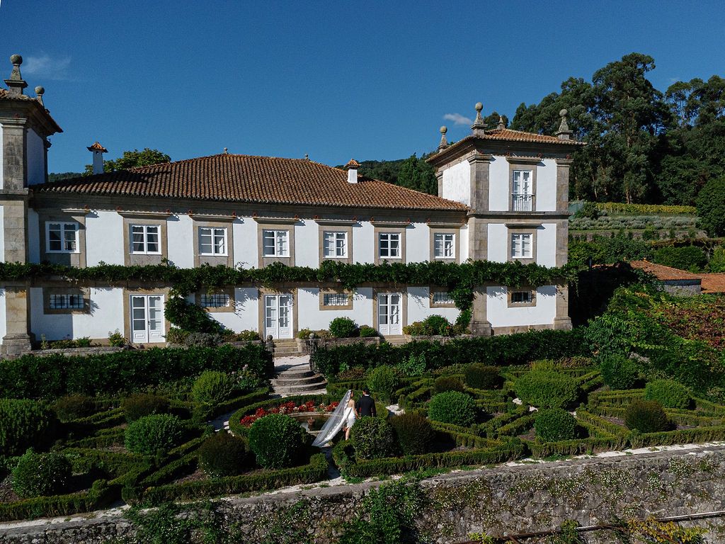 Long white Portuguese villa with traditional architecture nestled on a hillside surrounded by manicured gardens.