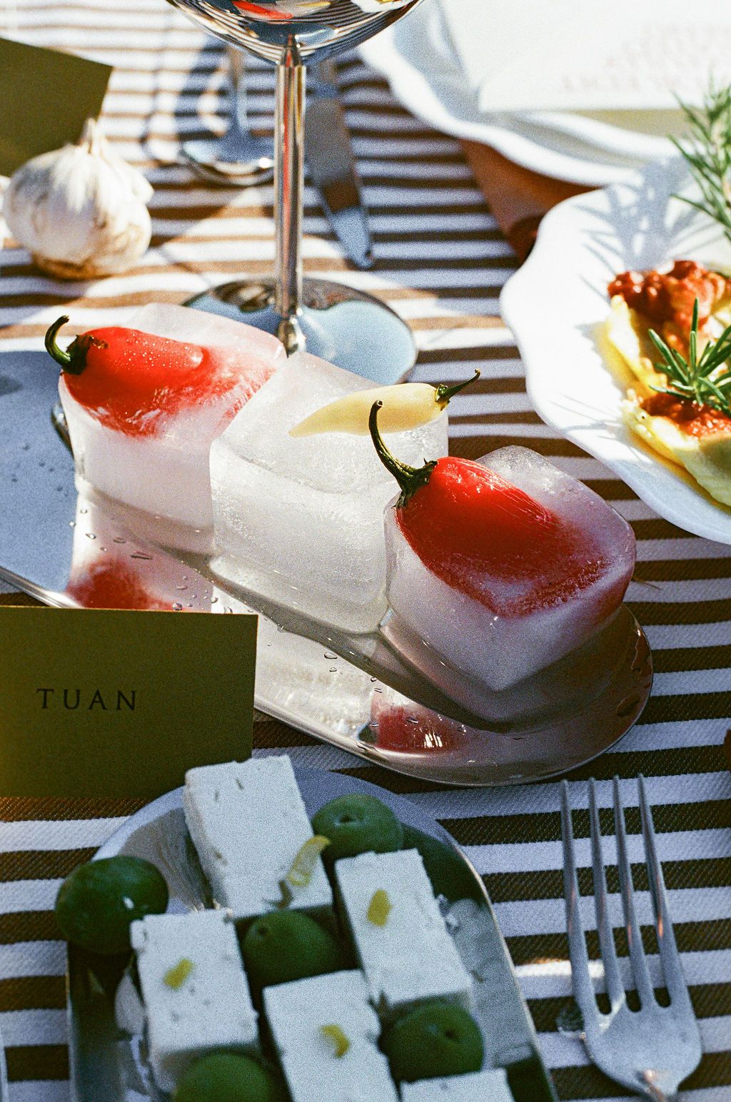 Close-up of gourmet appetizers and strawberries on white plates with striped tablecloth in Tuscany, Italy.