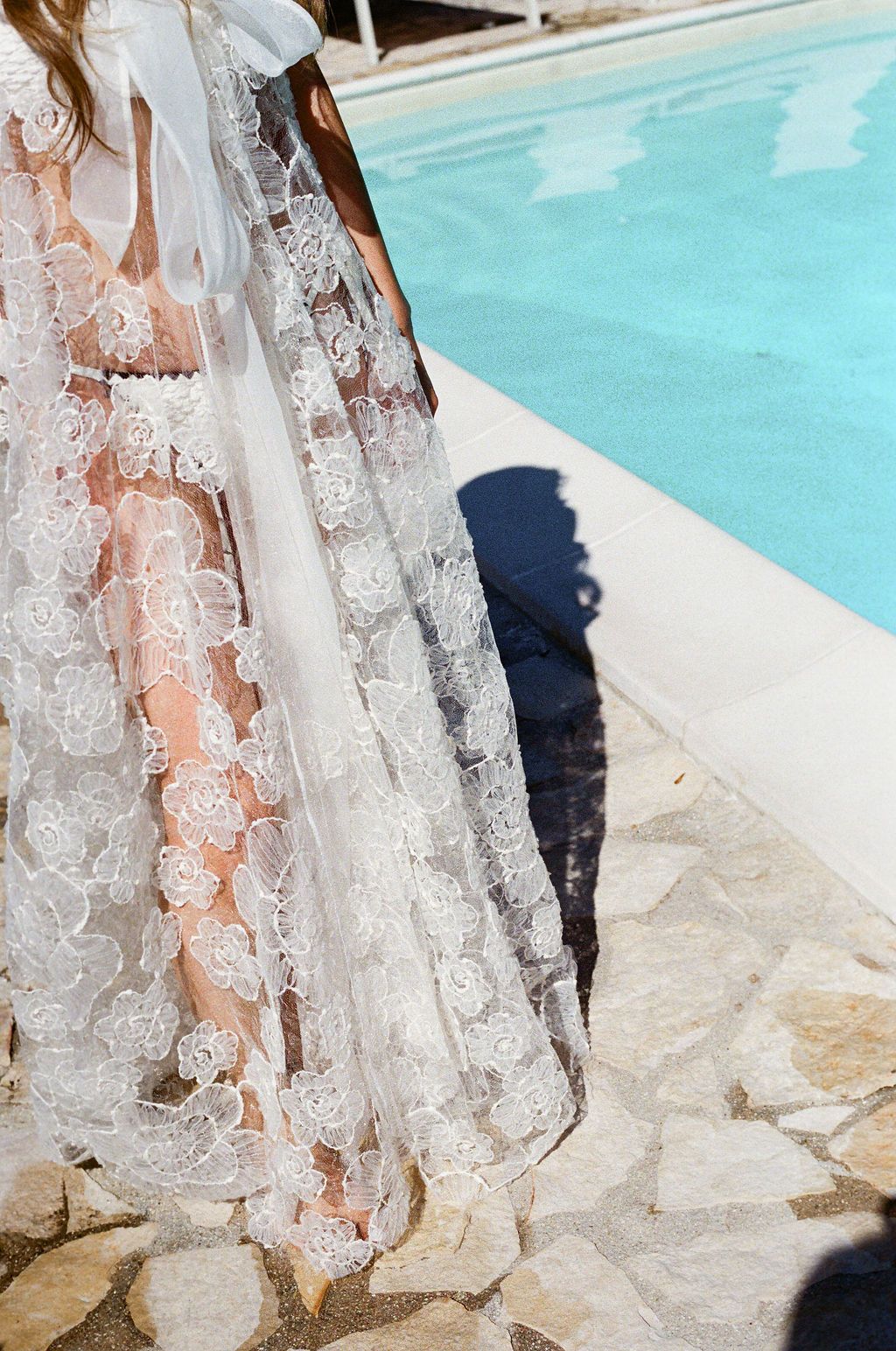 Delicate white lace fabric flowing near the edge of a swimming pool in Tuscany, Italy.