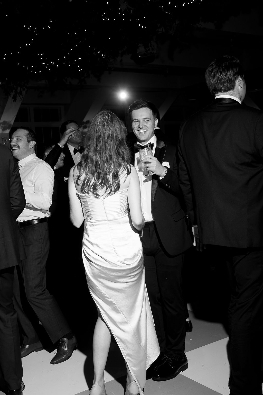 Black and white photo of couples dancing at a formal event with elegant attire.