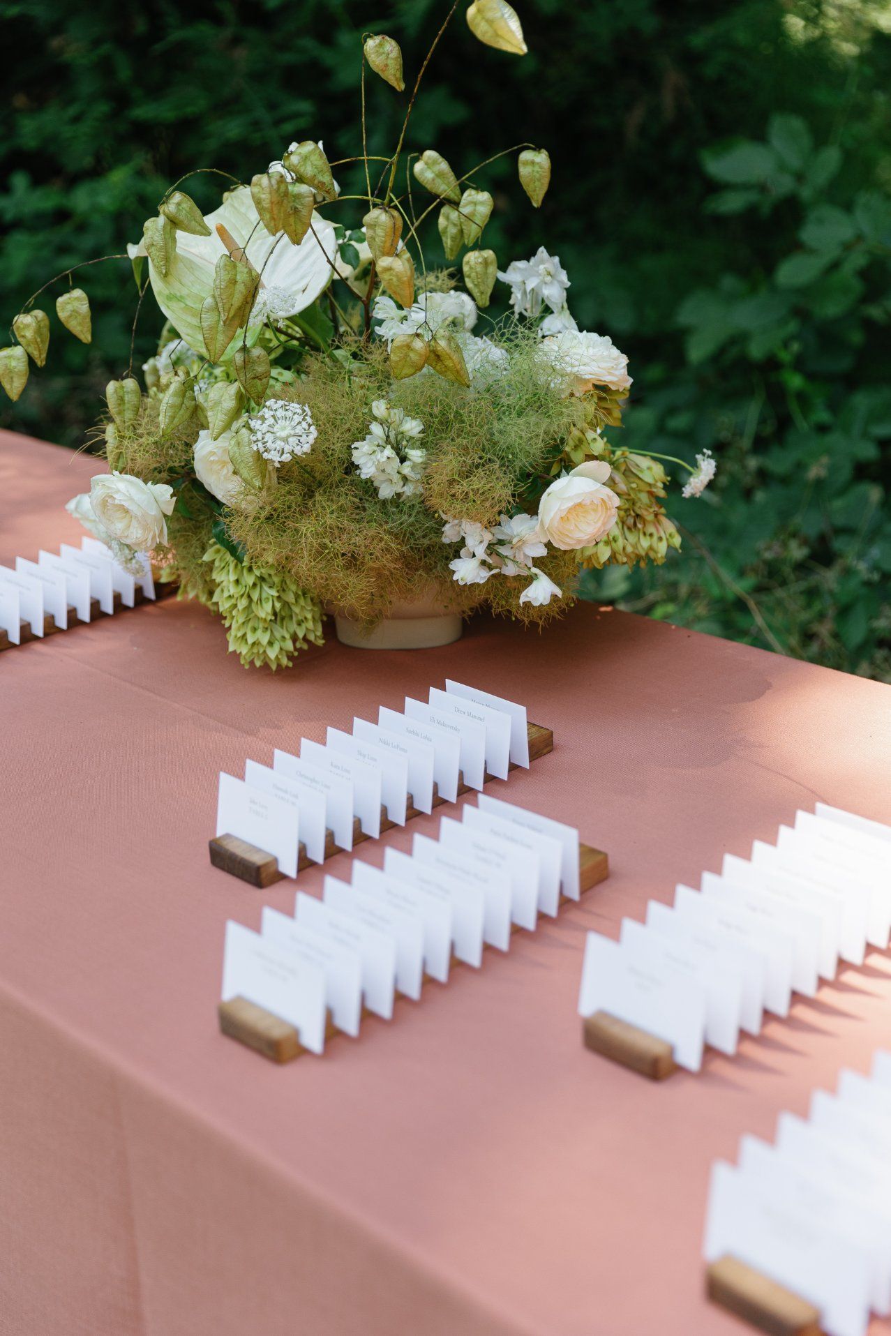 Row of white place cards arranged on a pink table with delicate floral arrangements.