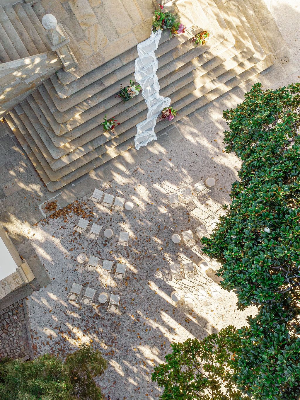 Stone steps decorated with greenery and flowers create a romantic garden pathway in dappled sunlight.