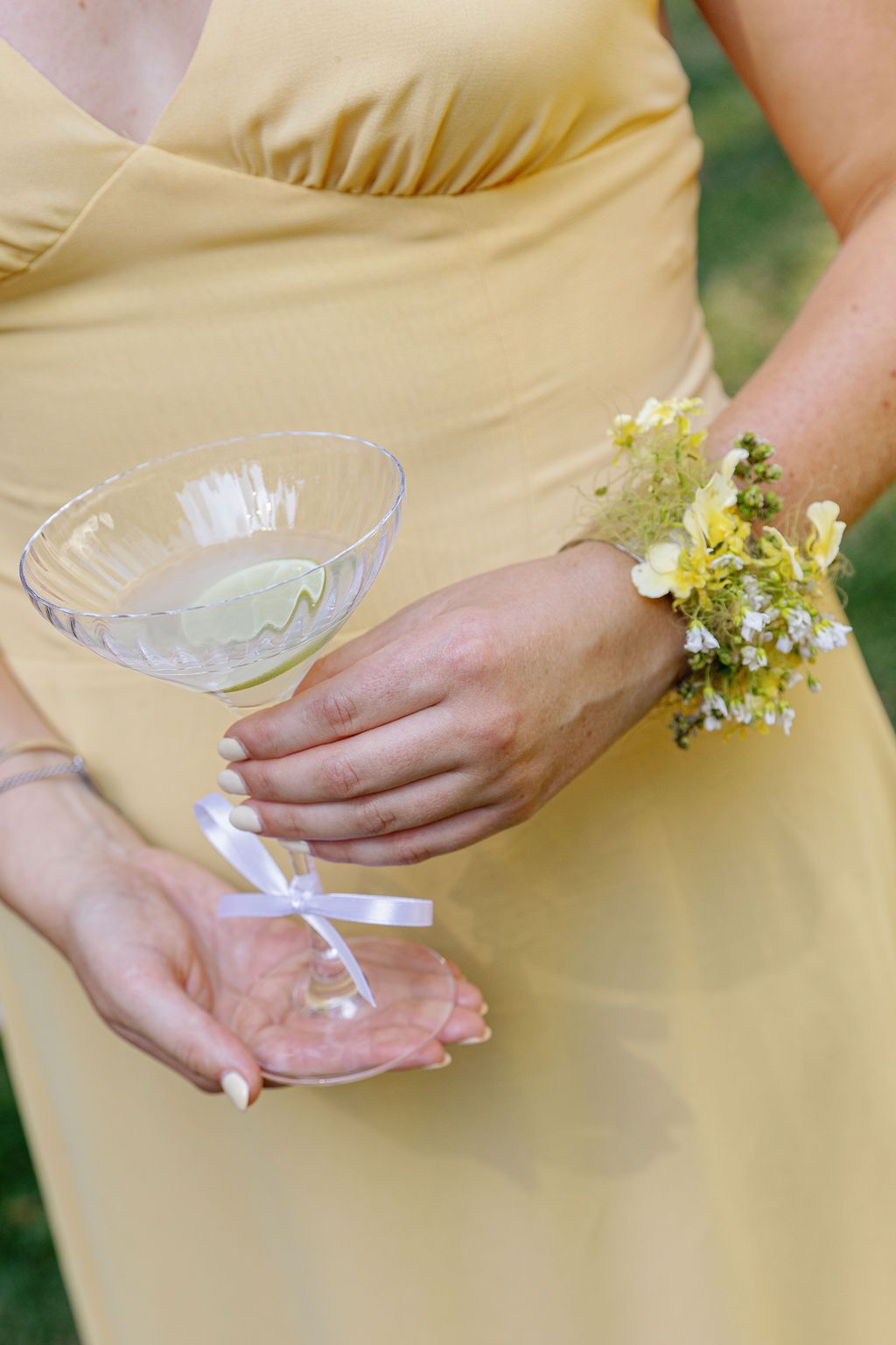 Close-up of hands holding delicate glass bowls against a soft yellow dress.