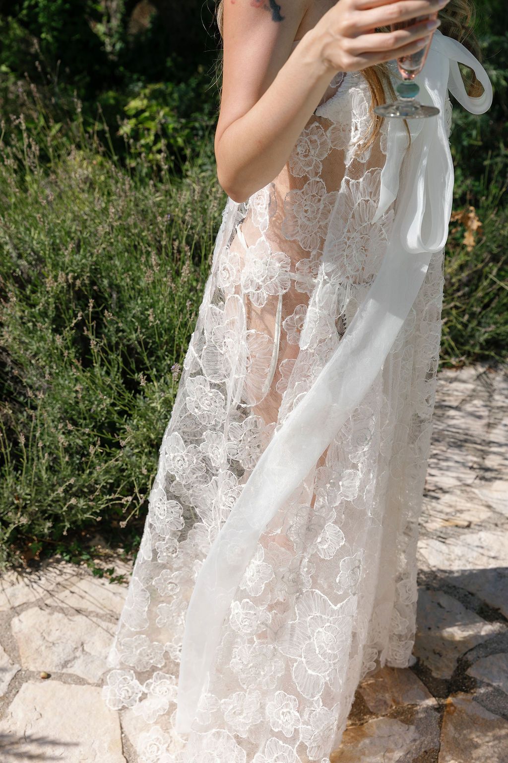 Ethereal white lace wedding dress with intricate floral patterns photographed outdoors in Tuscany, Italy.