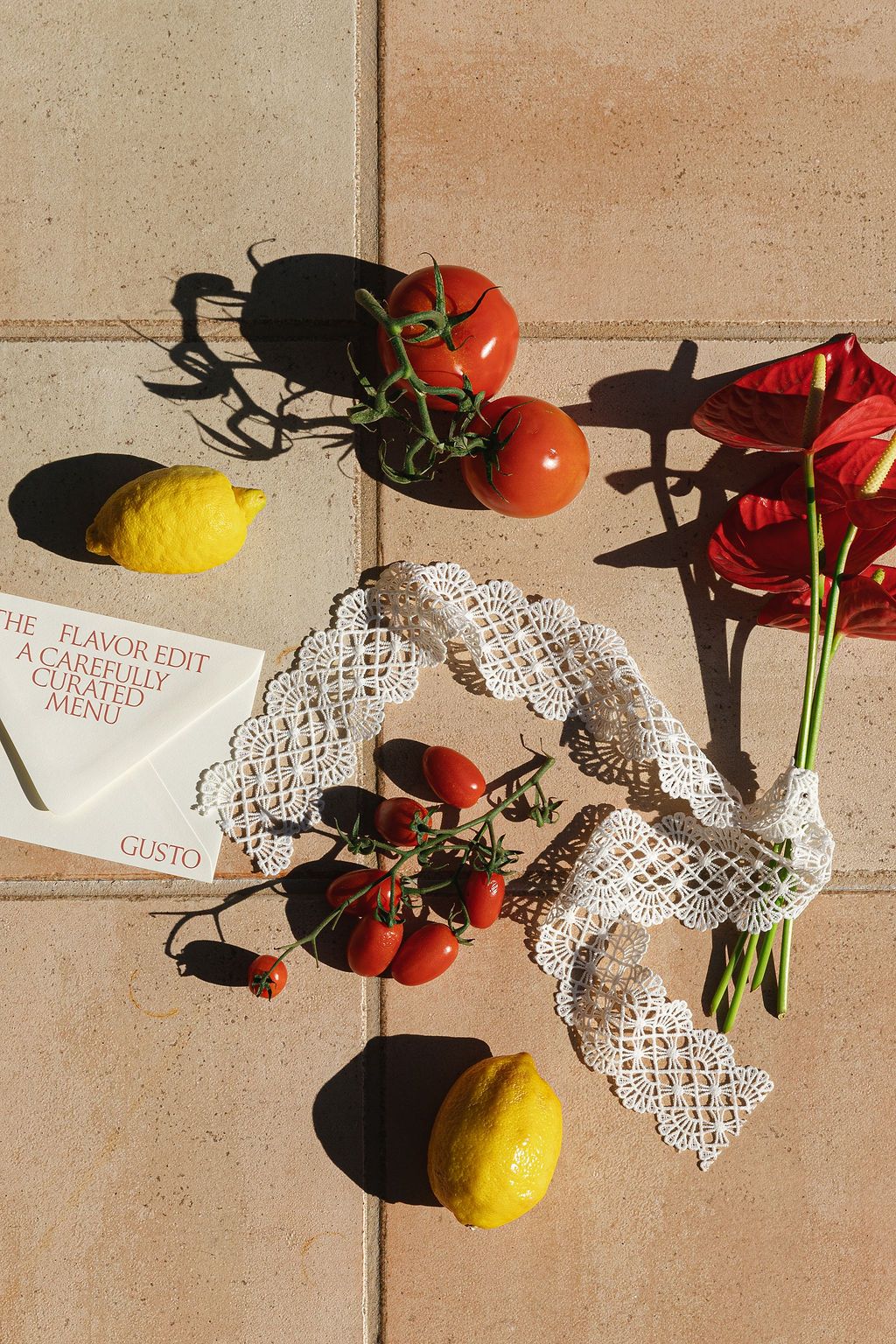 Fresh tomatoes and lemons arranged with lace doilies on a beige surface in Tuscany, Italy.