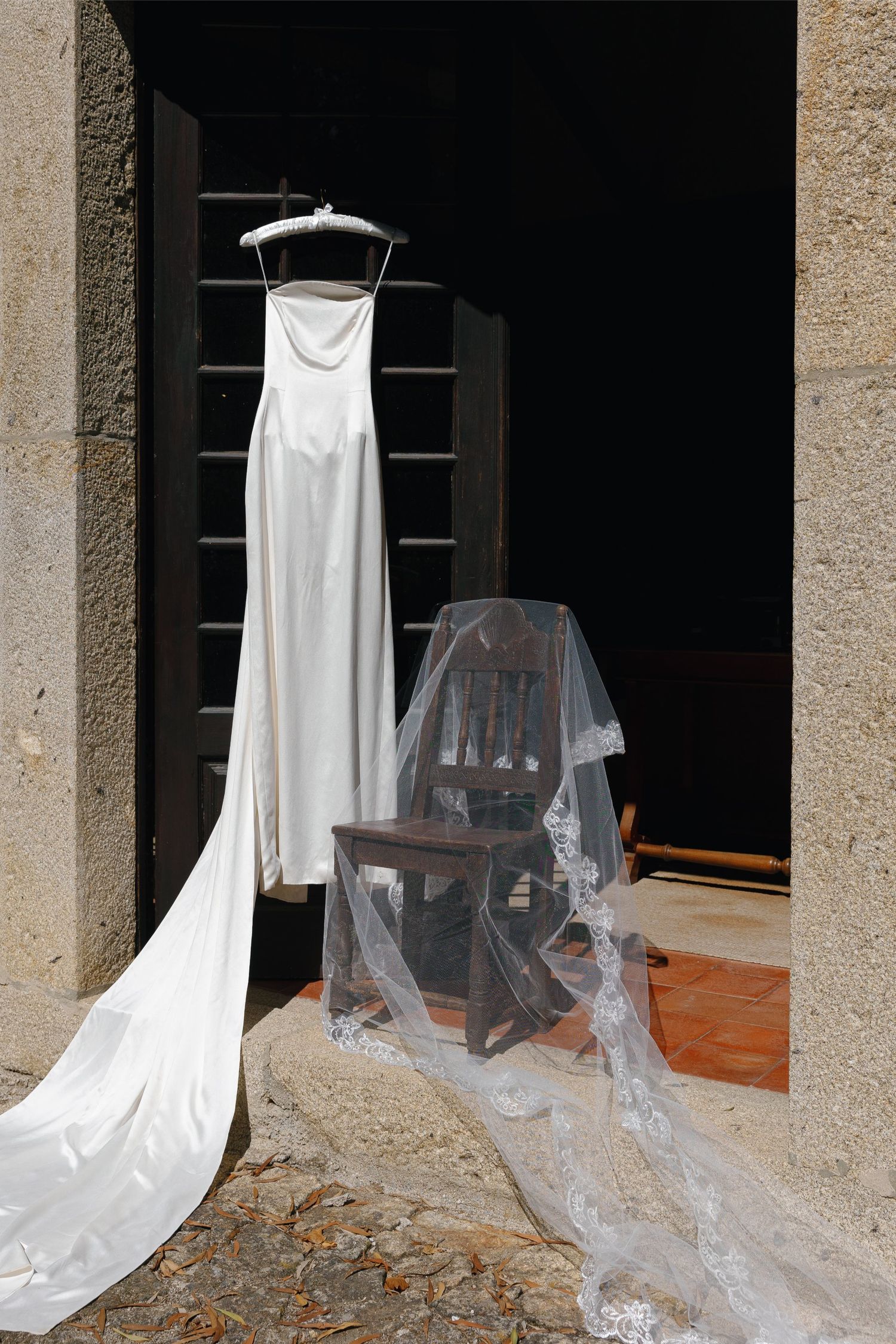 White fabric drapes and chairs create an eerie ghost-like display in a dimly lit stone archway setting in Portugal.