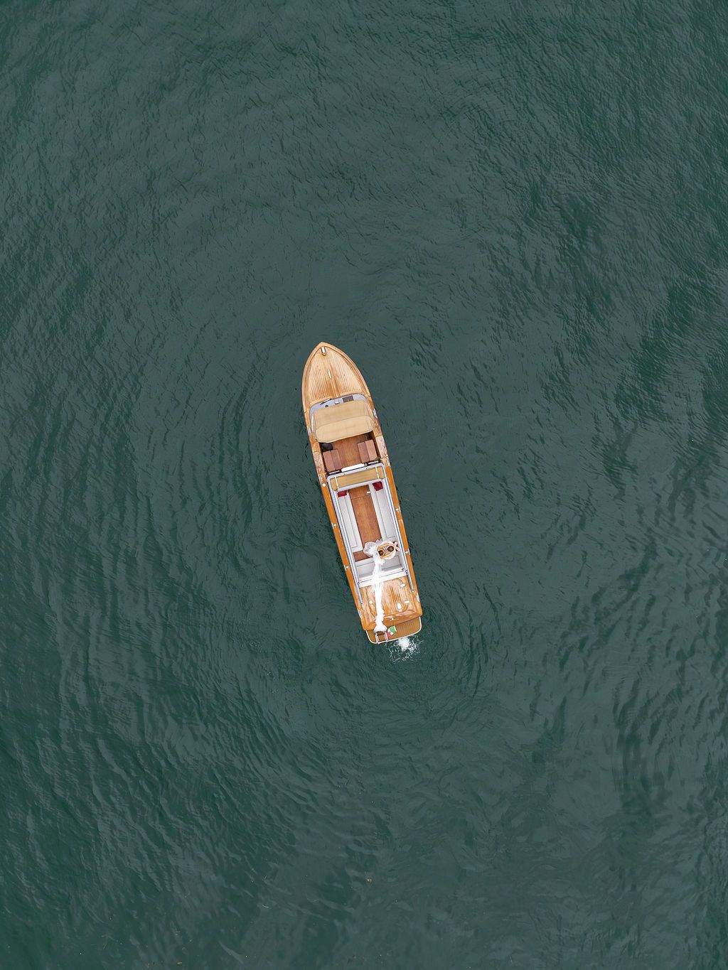 Aerial view of wooden boats floating on dark turquoise waters of Lake Como.