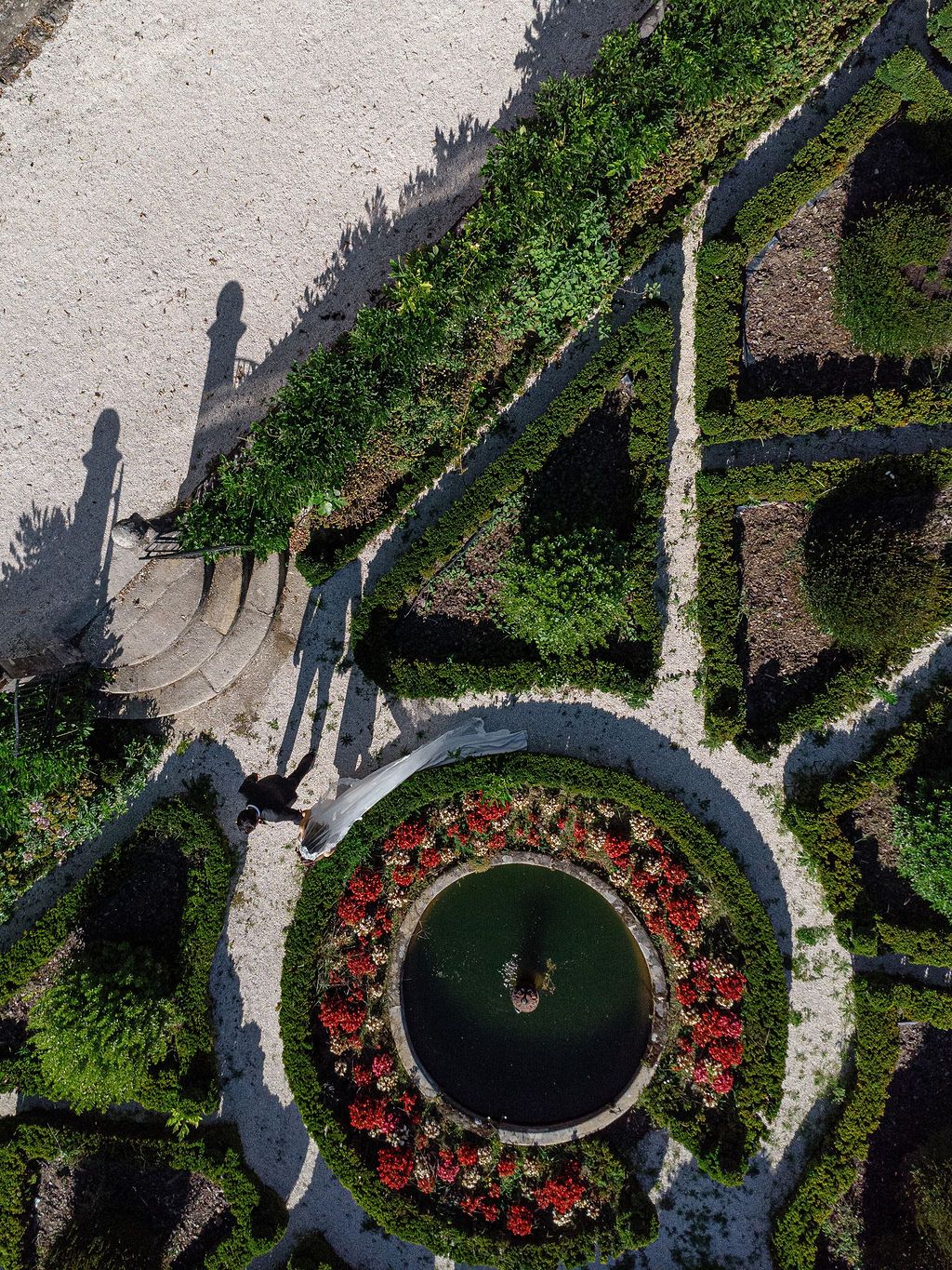 Aerial view of a circular garden path surrounded by red flowers and green landscaping at estate in Portugal.
