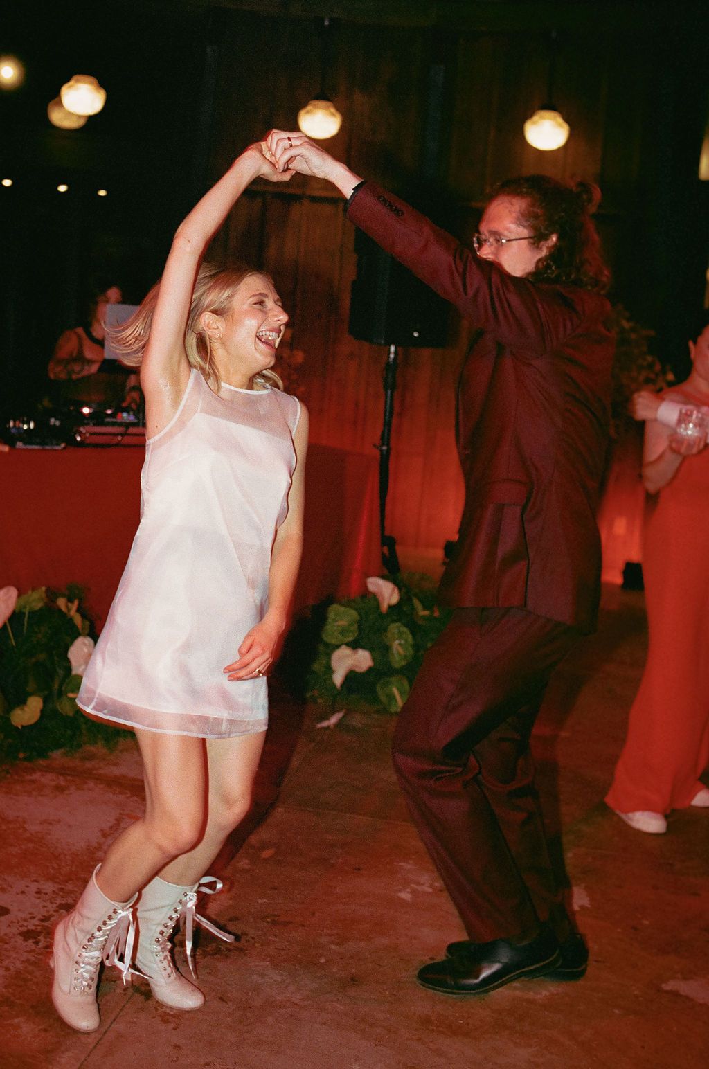 Wedding reception dance party with guests dancing under warm lighting.