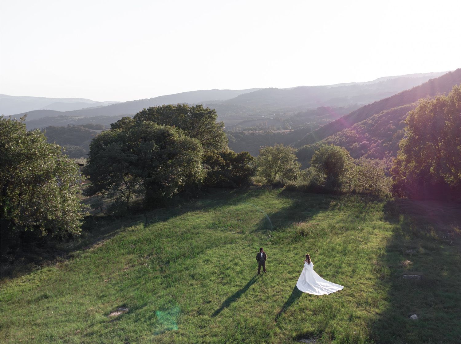 A panoramic sequence of rolling green hills and meadows in late afternoon sunlight with long shadows stretching across the grass in Tuscany.