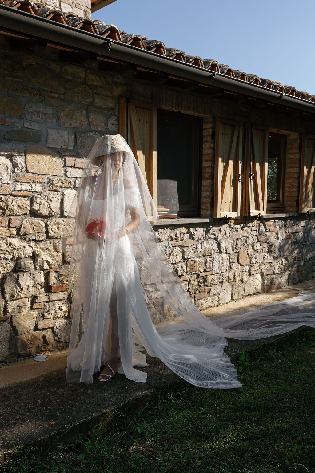 Flowing white veils create ghostly silhouettes against stone walls in natural daylight in Tuscany, Italy.