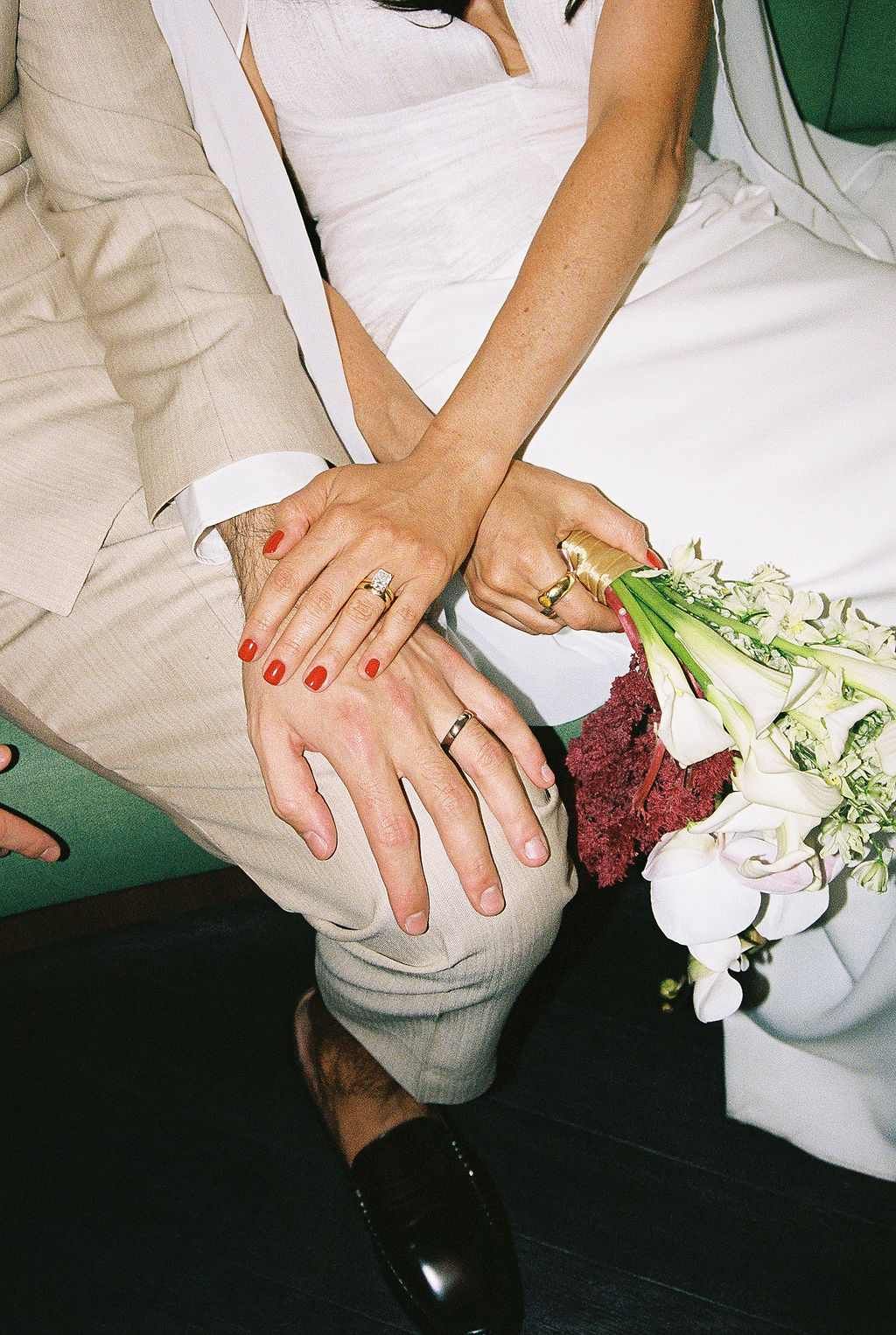 Close-up sequence showing hands with red nail polish holding a white floral bouquet against a dark background.