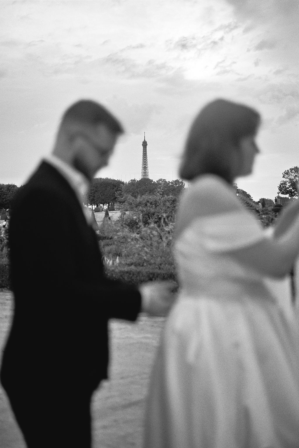 Silhouettes of a couple with the Eiffel Tower visible in the background at dusk in Paris, France.
