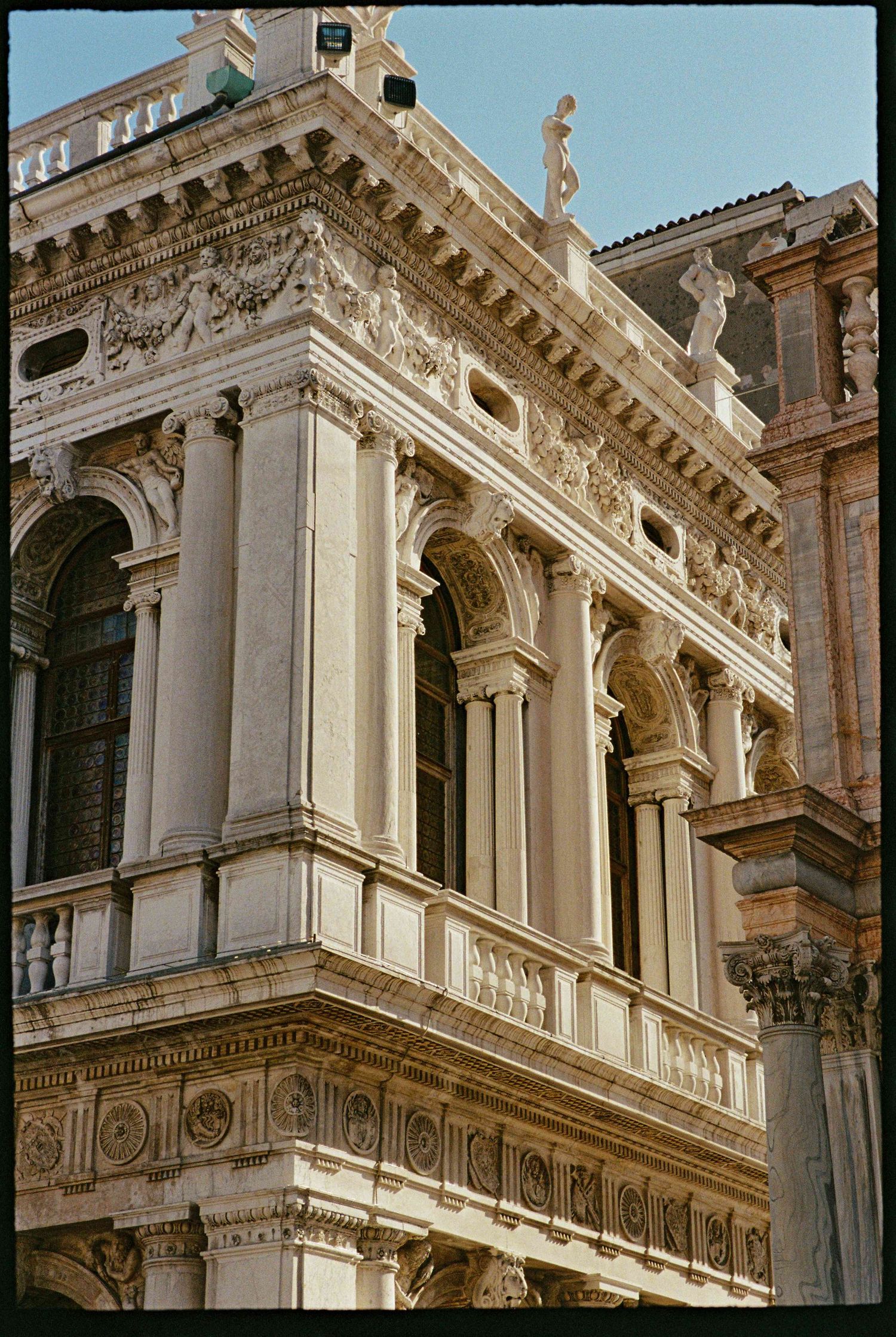Ornate Renaissance facade with classical columns, arched windows, and decorative sculptures in Venice, Italy.