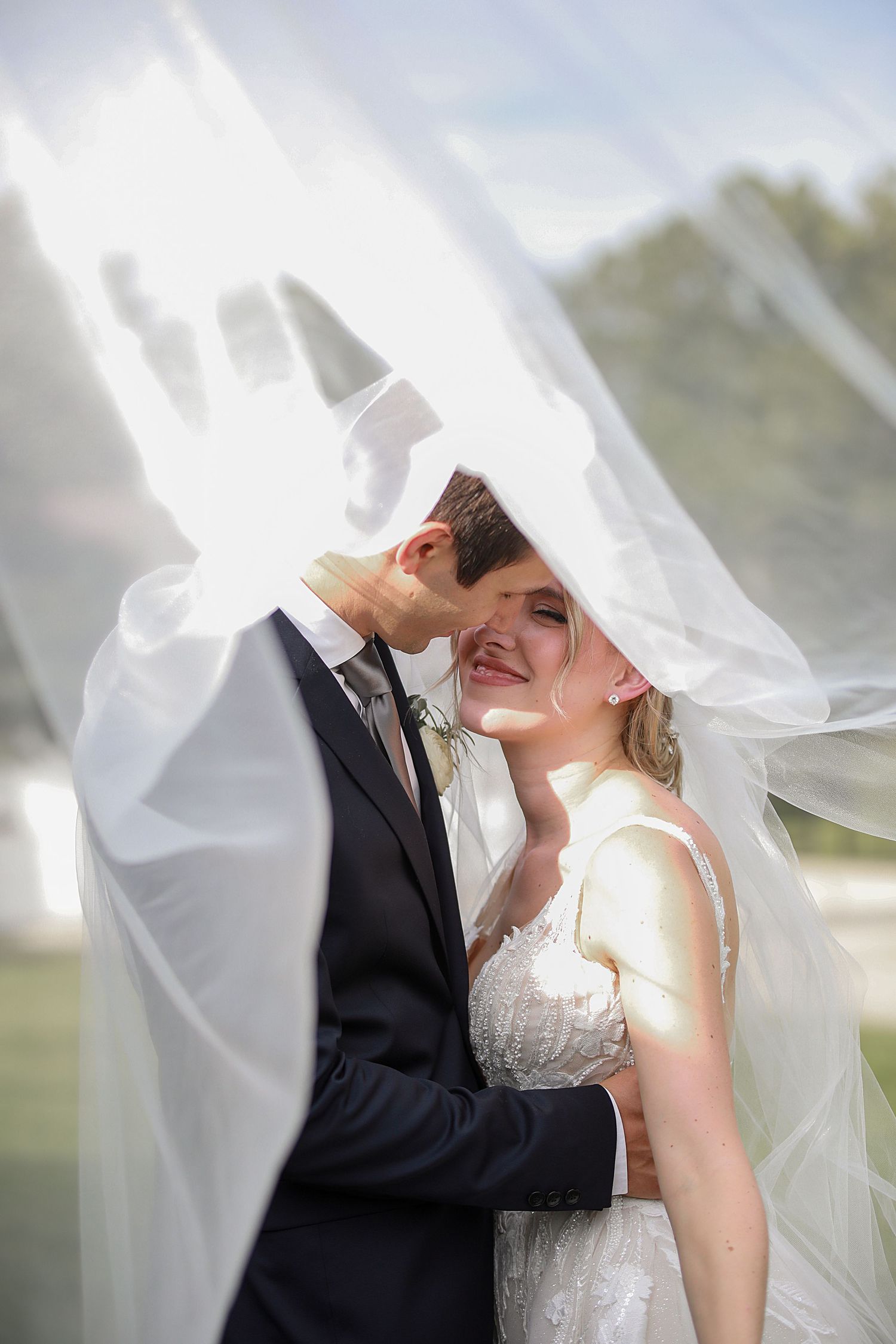 A joyful wedding moment captured under flowing white veil in natural outdoor lighting. Wedding Photographer in Cleveland Ohio