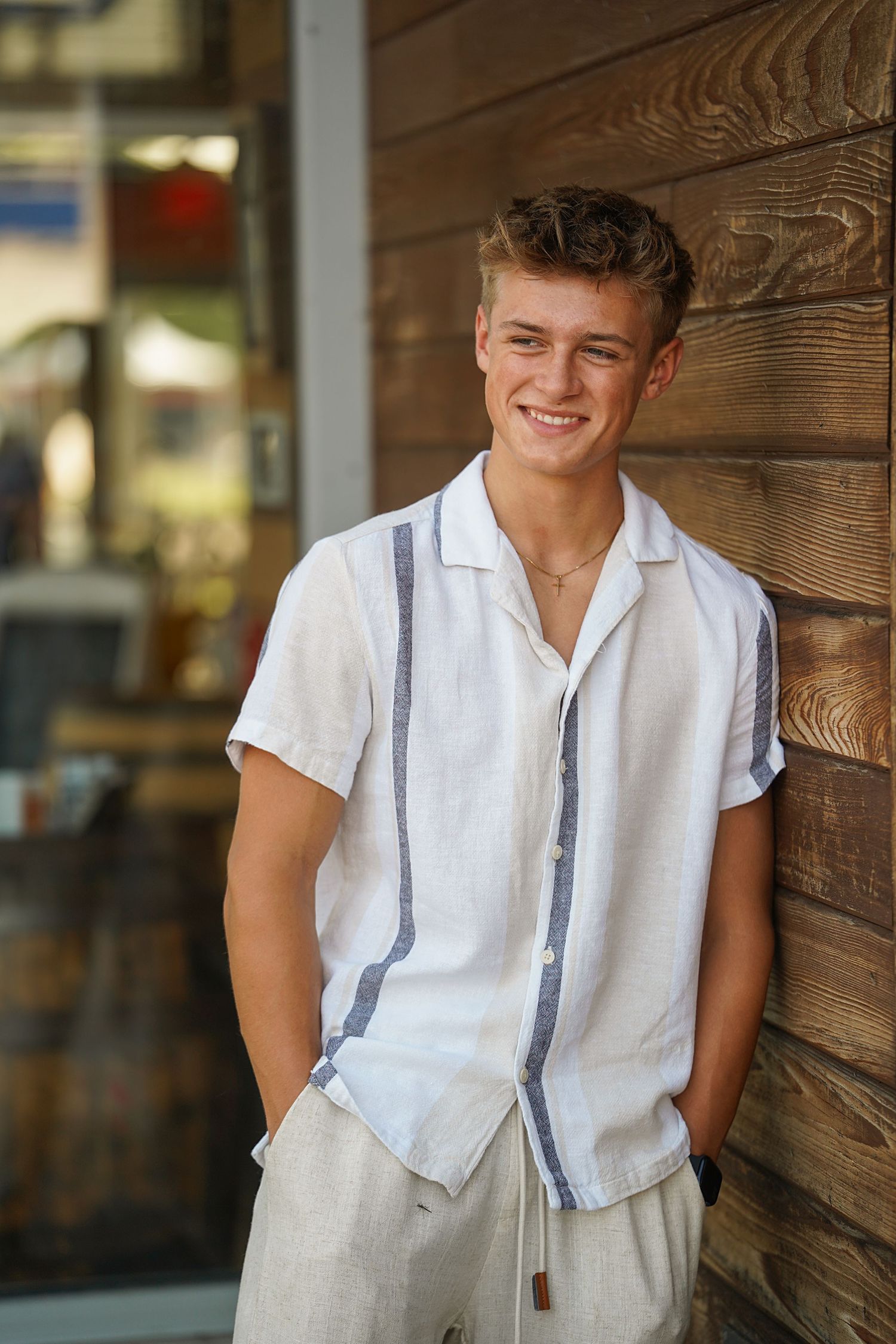 Vintage style portrait of someone in casual white shirt and suspenders against rustic wooden wall.