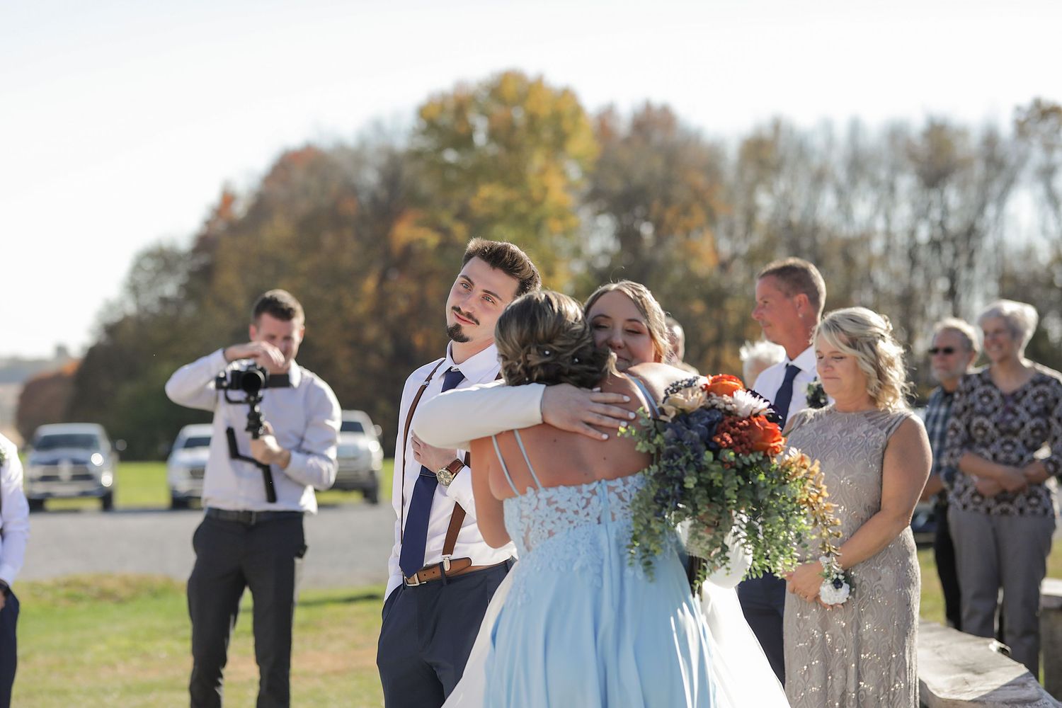 Joyful celebration during outdoor autumn wedding ceremony with white pergola in background.